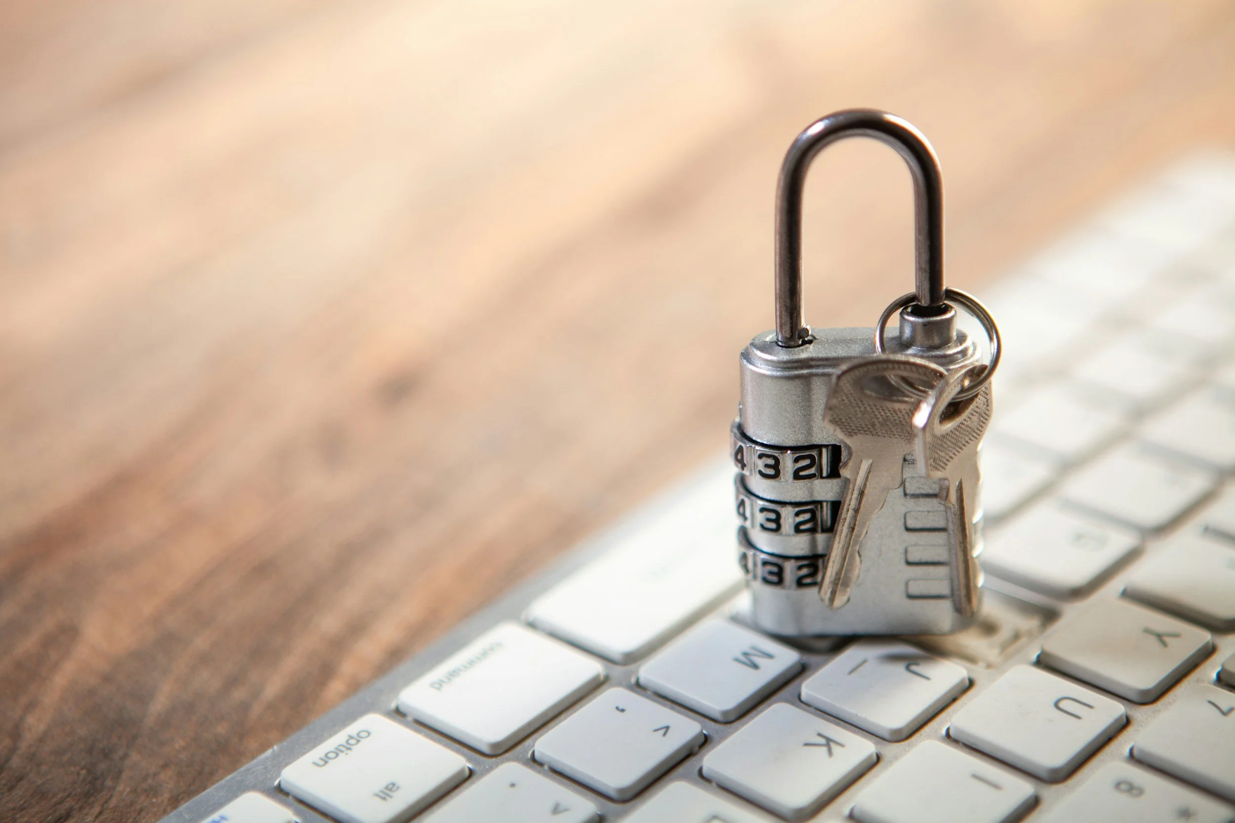 A padlock with keys attached sitting on a computer keyboard.
