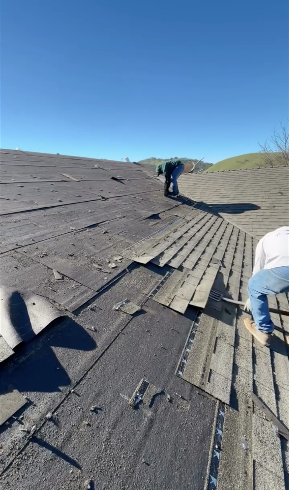 Workers repairing or replacing roof shingles on a roof under in Morgan Hill, CA.