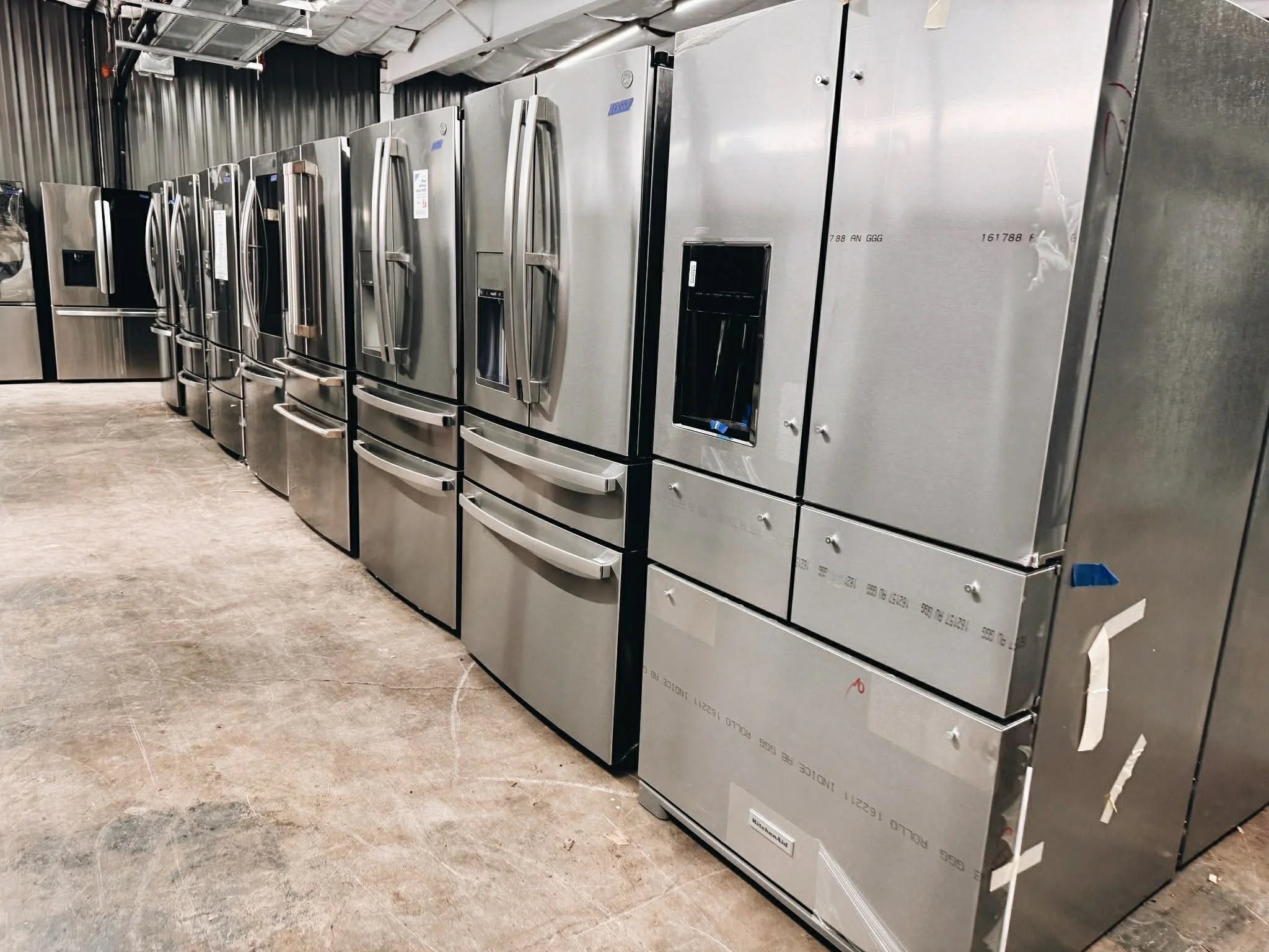 Row of refrigerators on discount sale at Annie & Al's Appliance Outlet, a Huntsville discount appliance store known for the cheapest fridges in Huntsville, Alabama