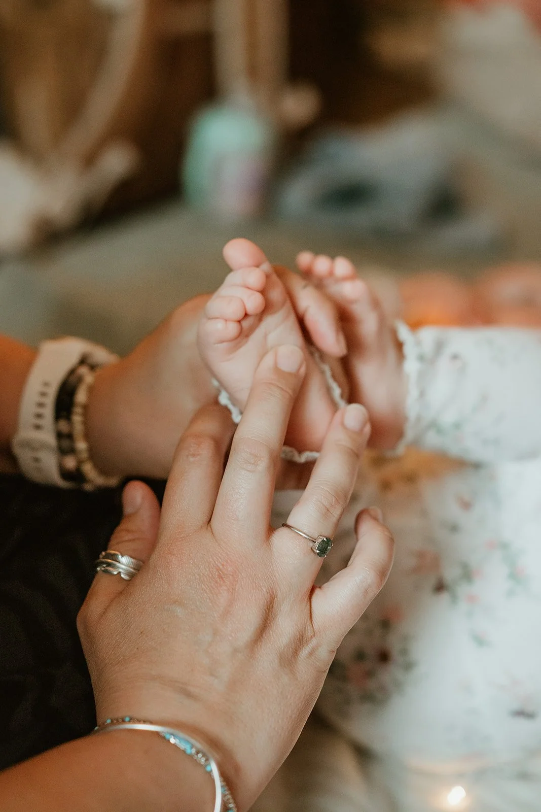 A close-up of an adult's hand gently holding a baby's hand in a hospital or care setting.