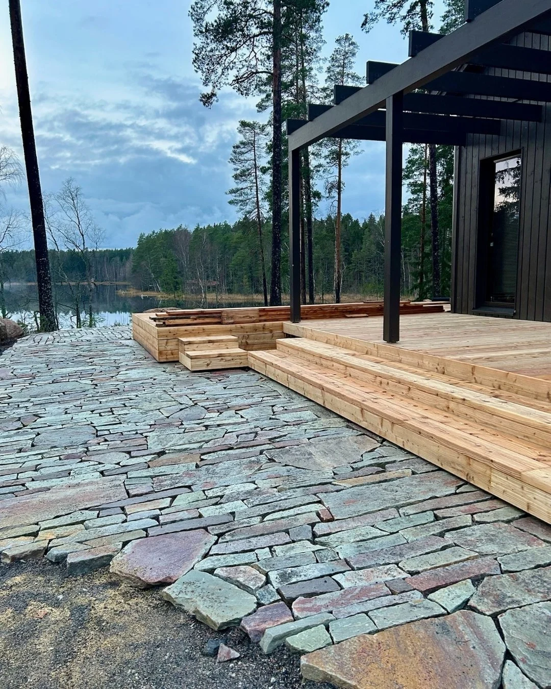 Kuva pihasta jossa puinen terassi sekä luonnonkivi laatoitusta.