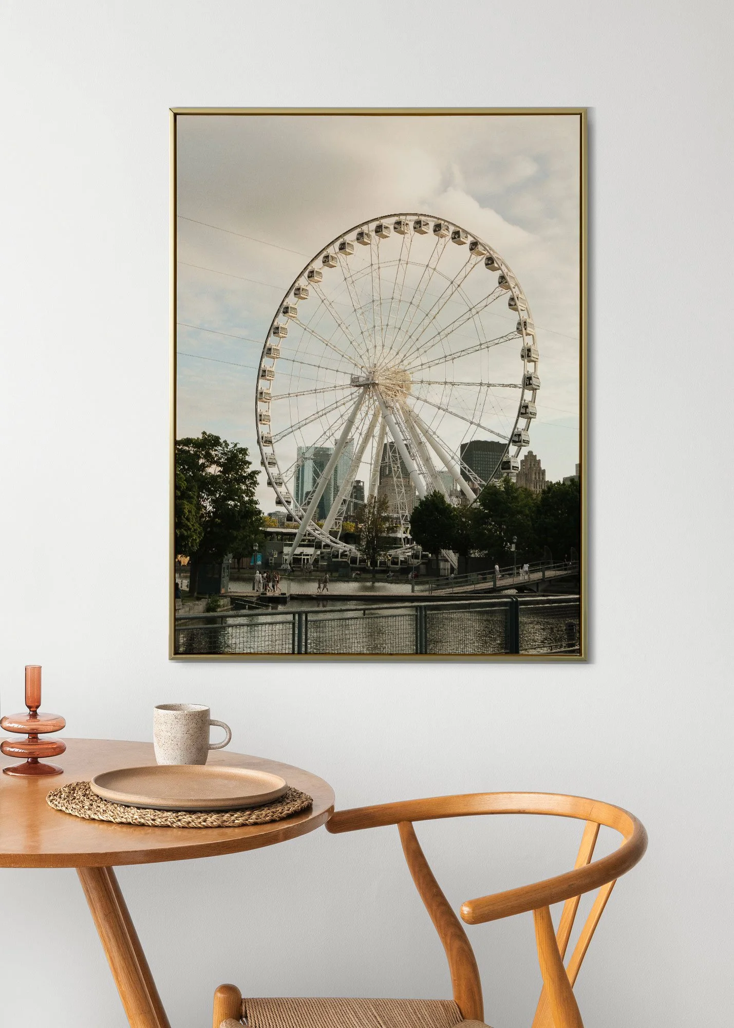 A large framed photograph of a Ferris wheel in an urban park on a partly cloudy day, hanging on a white wall.