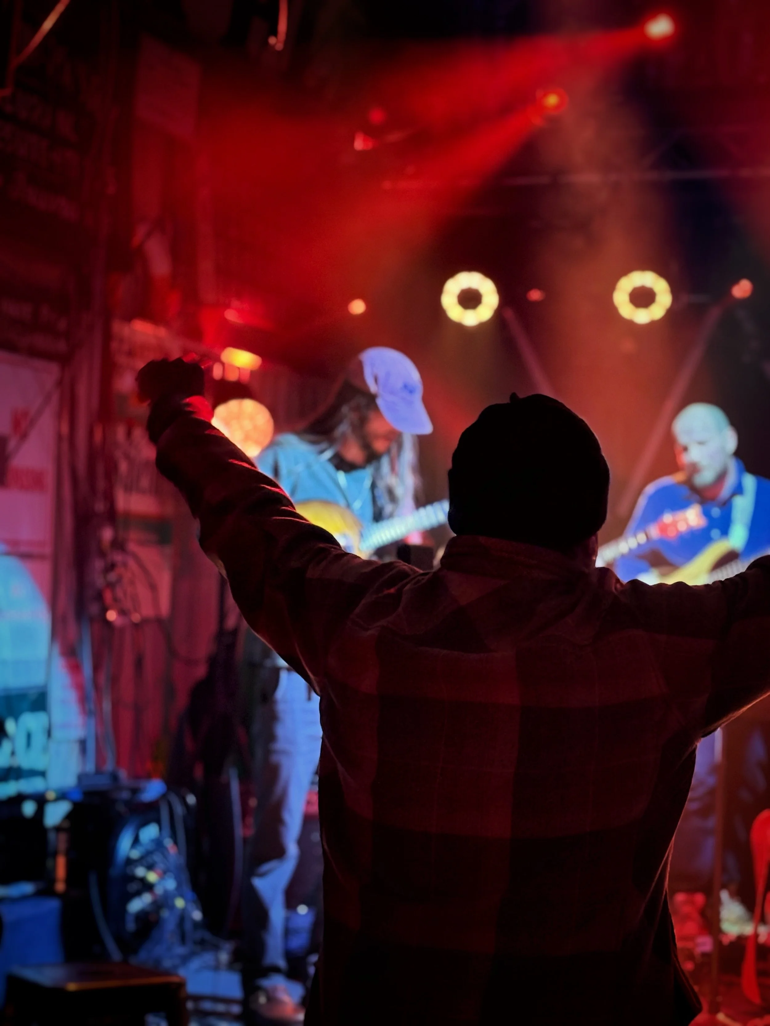 A man in the foreground facing the stage as a band plays