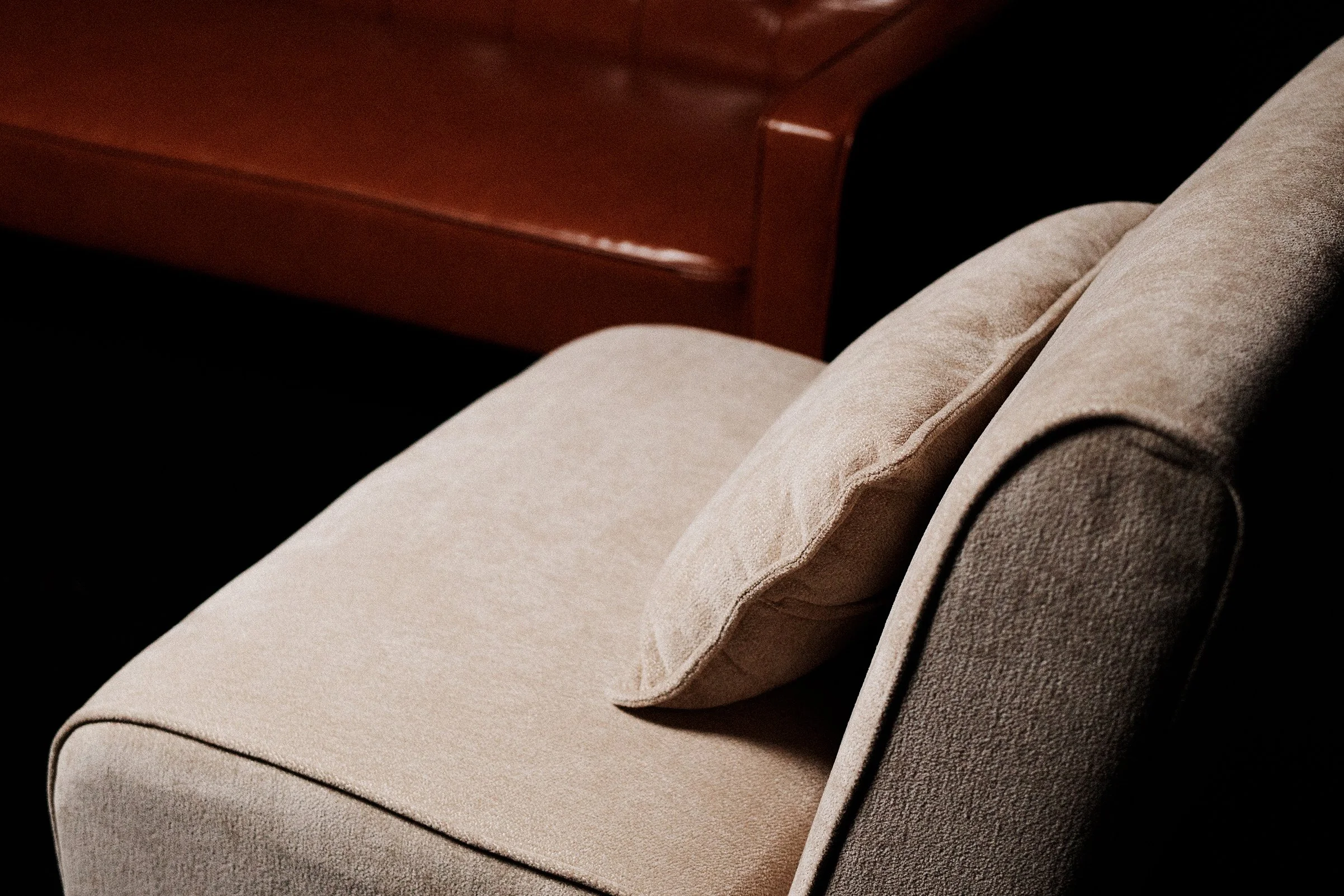 Close-up of a beige upholstered armchair with dark piping details.