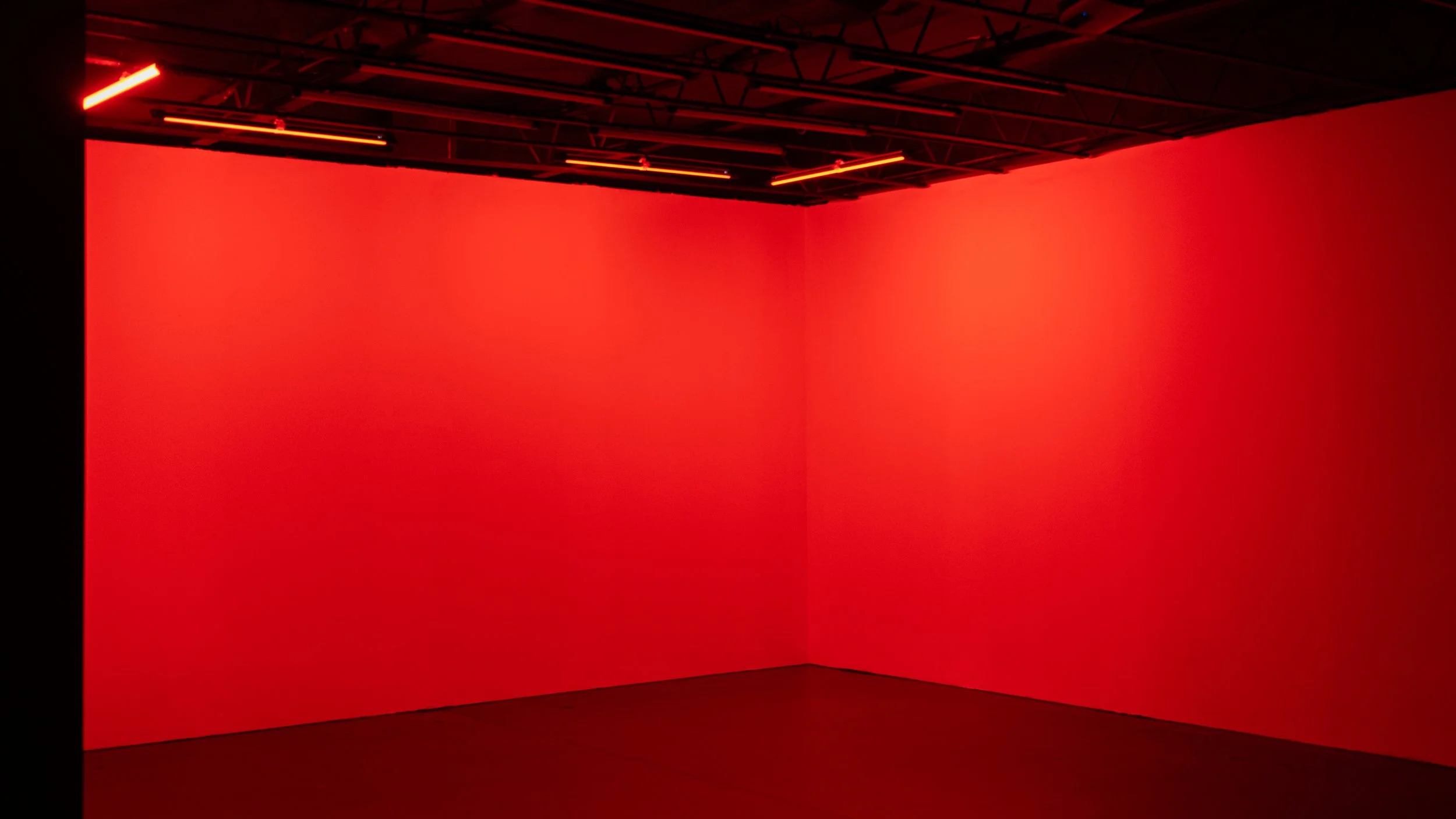 An empty room with red walls, red ceiling, and red lighting fixtures.
