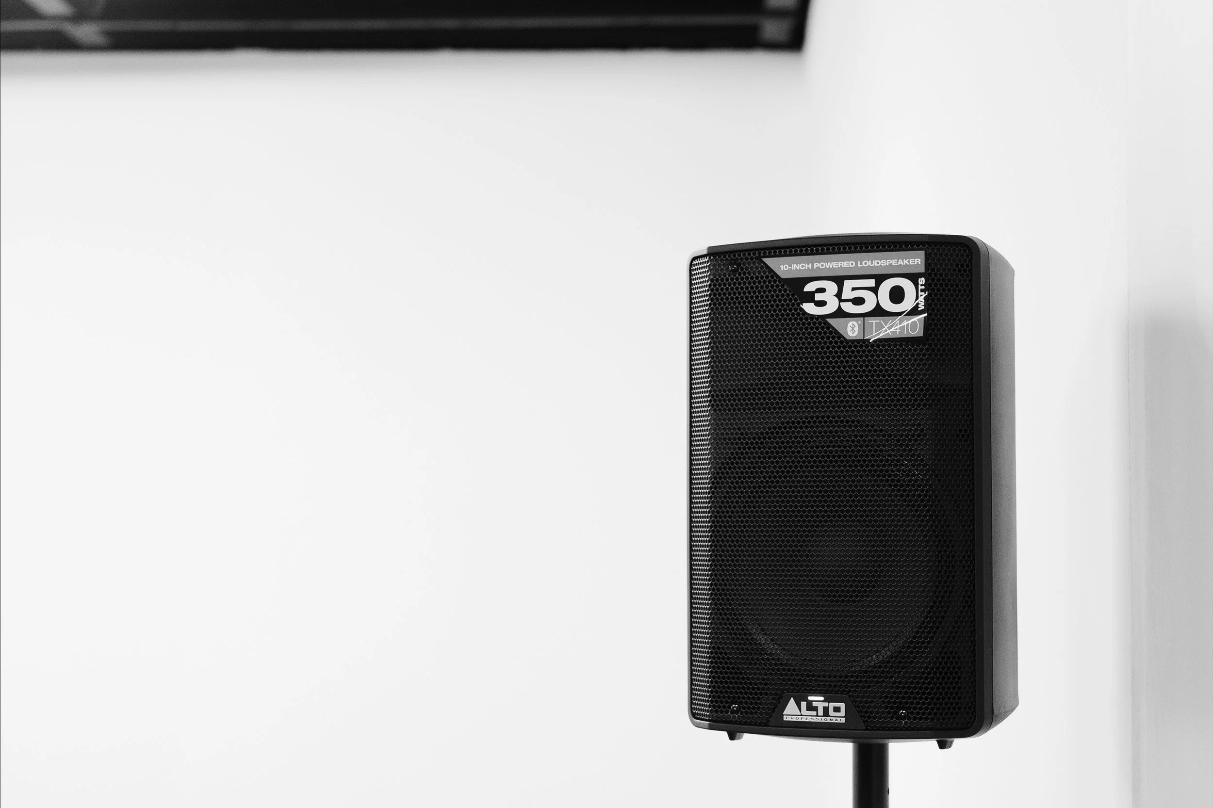 Black Alto professional 10-inch powered loudspeaker mounted on a stand against a white wall.