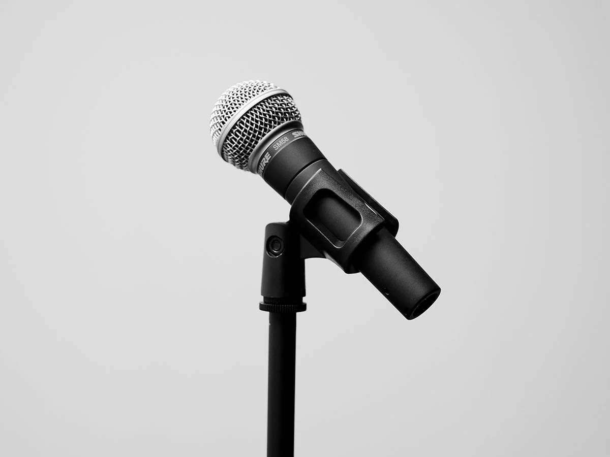 A black microphone on a stand against a plain light gray background.