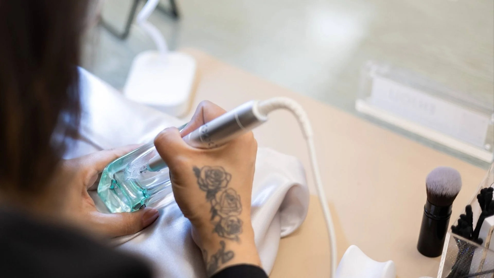 A woman personalizing a perfume bottle with a hand engraver