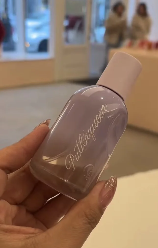 A hand holding a clear bottle with a name custom engraved on it