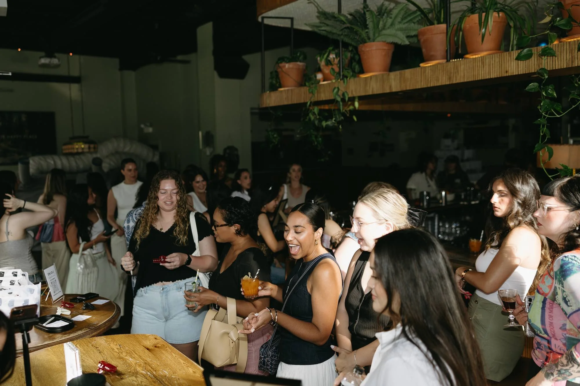 Group of women at an event watching Enjoli engrave mirrors live.