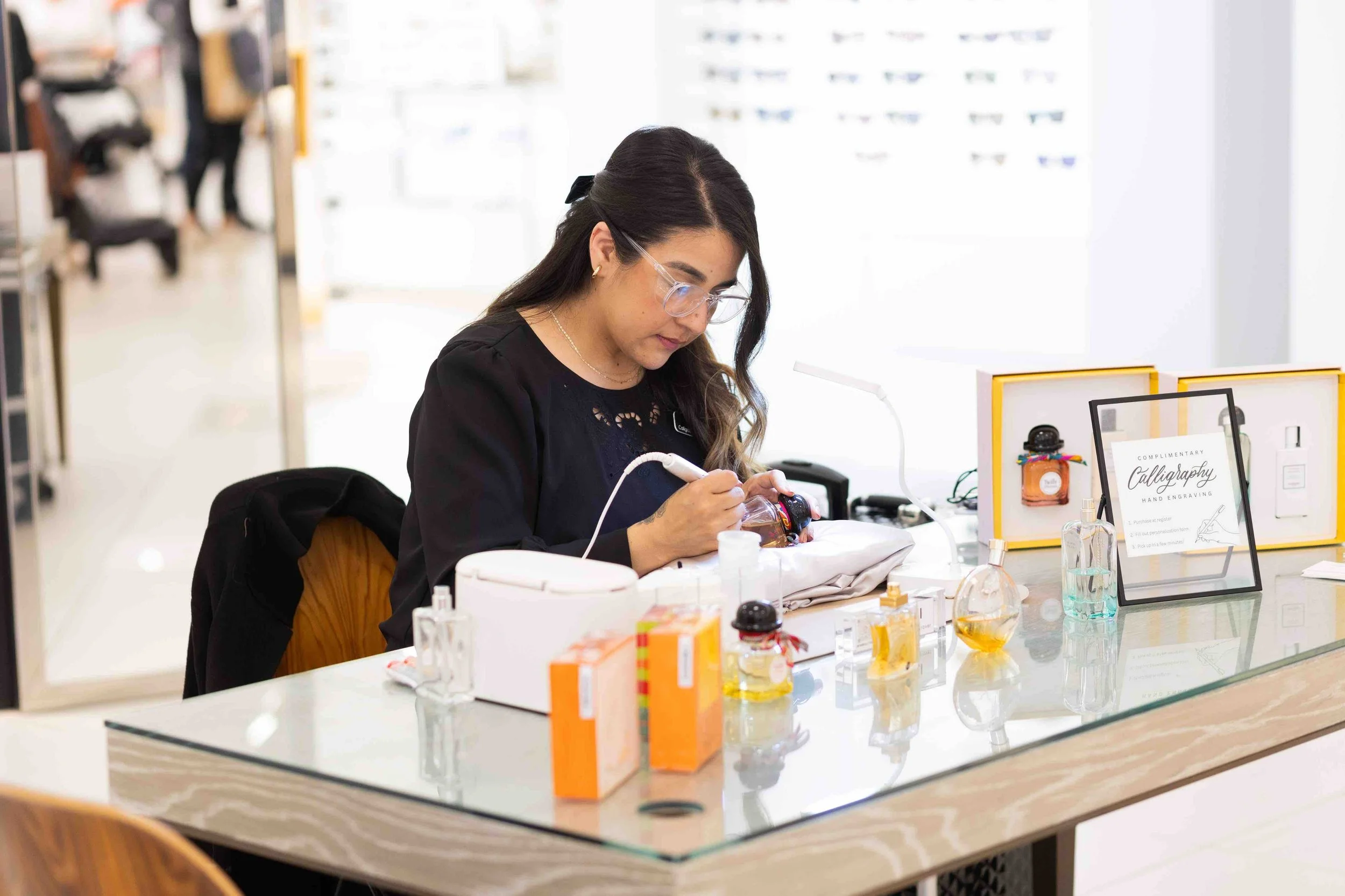 Enjoli Villa laser engraving perfume bottles at a brand activation event