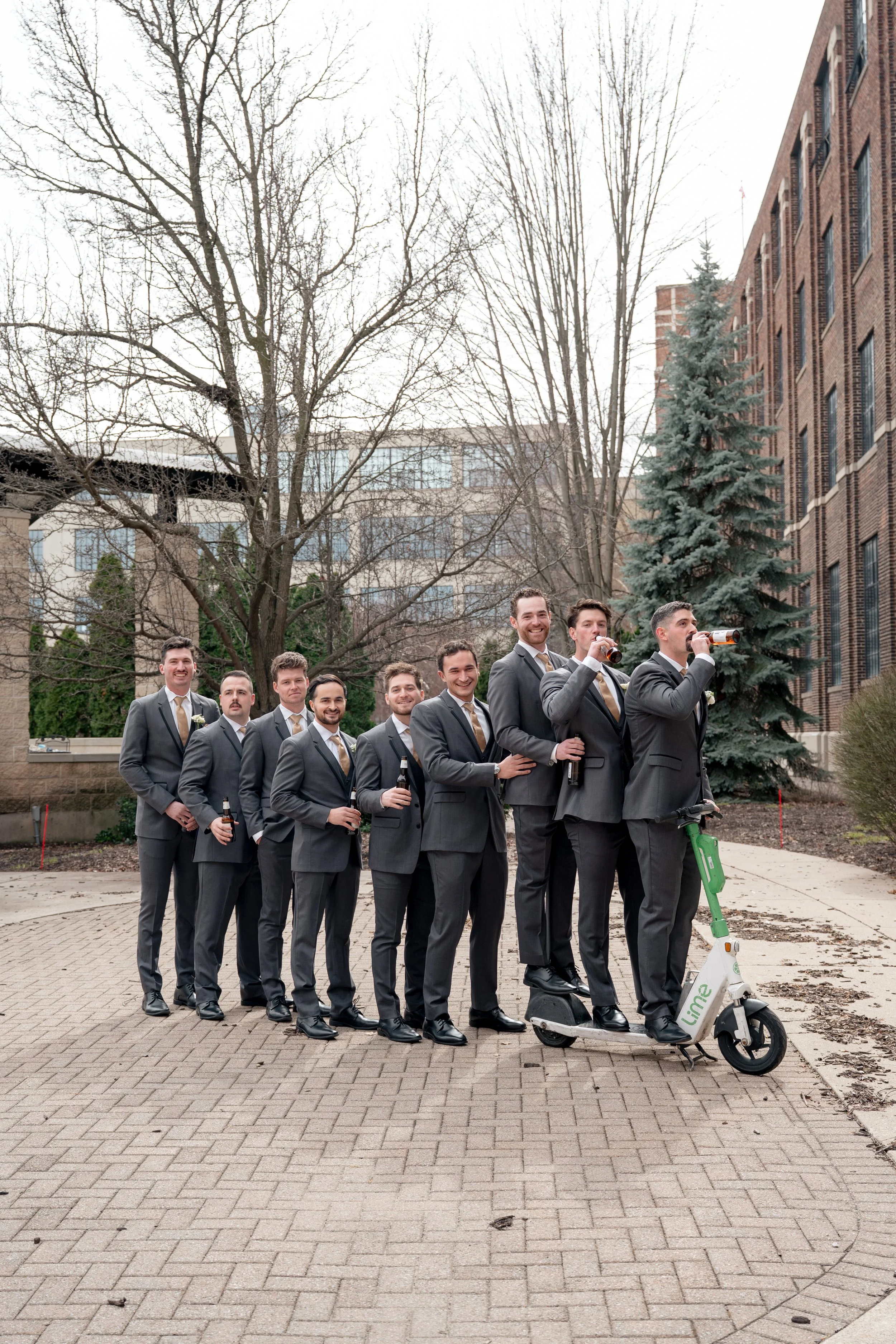 Groom and groomsmen drinking beers lined up with a scooter.