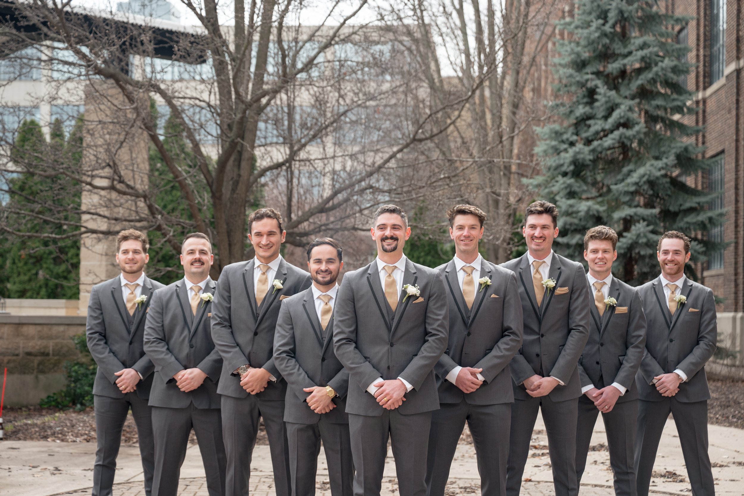 Groom and groomsmen smiling at the camera with the groom at the center.