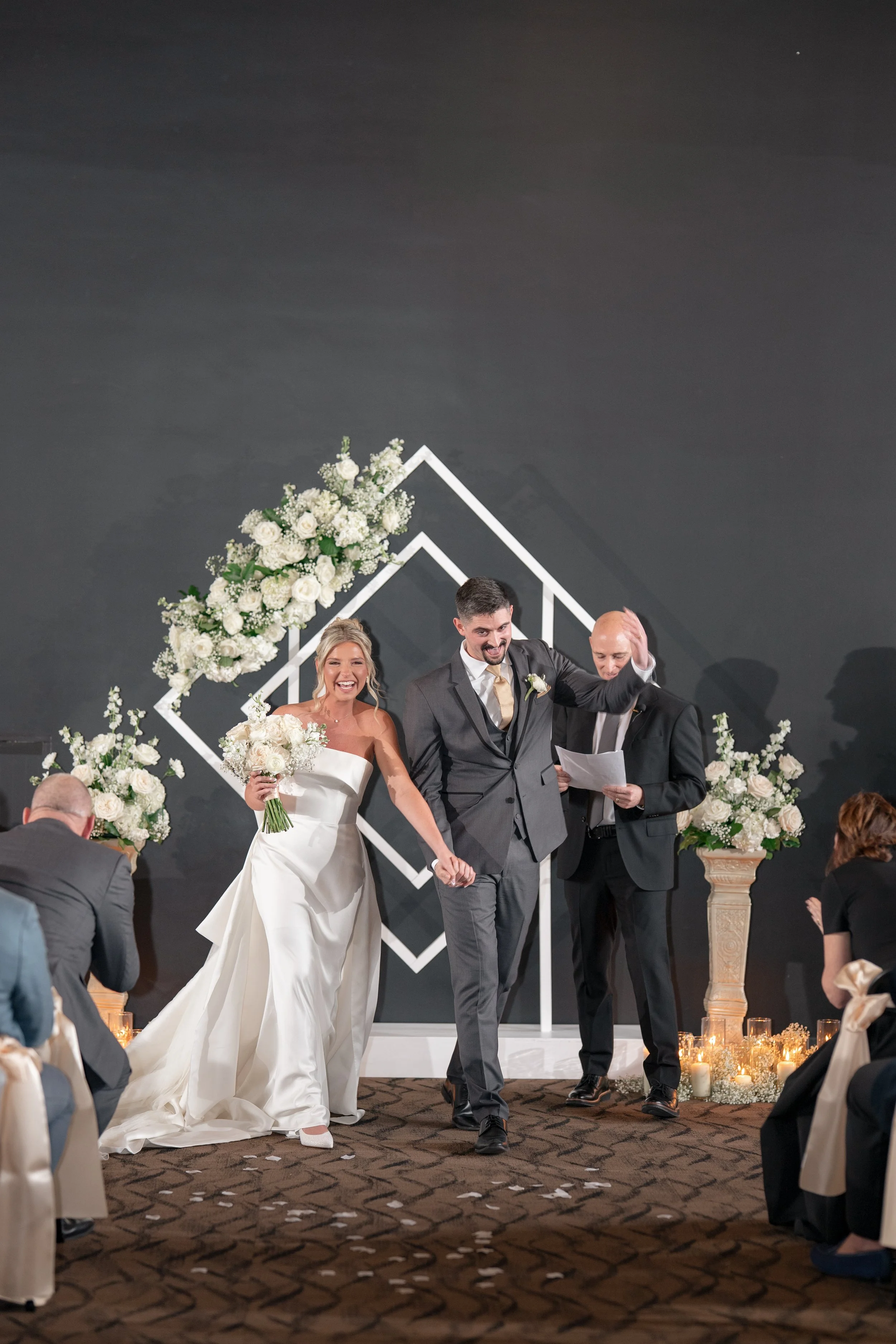 Bride and groom celebrating and holding hands walking back down the aisle after the ceremony.