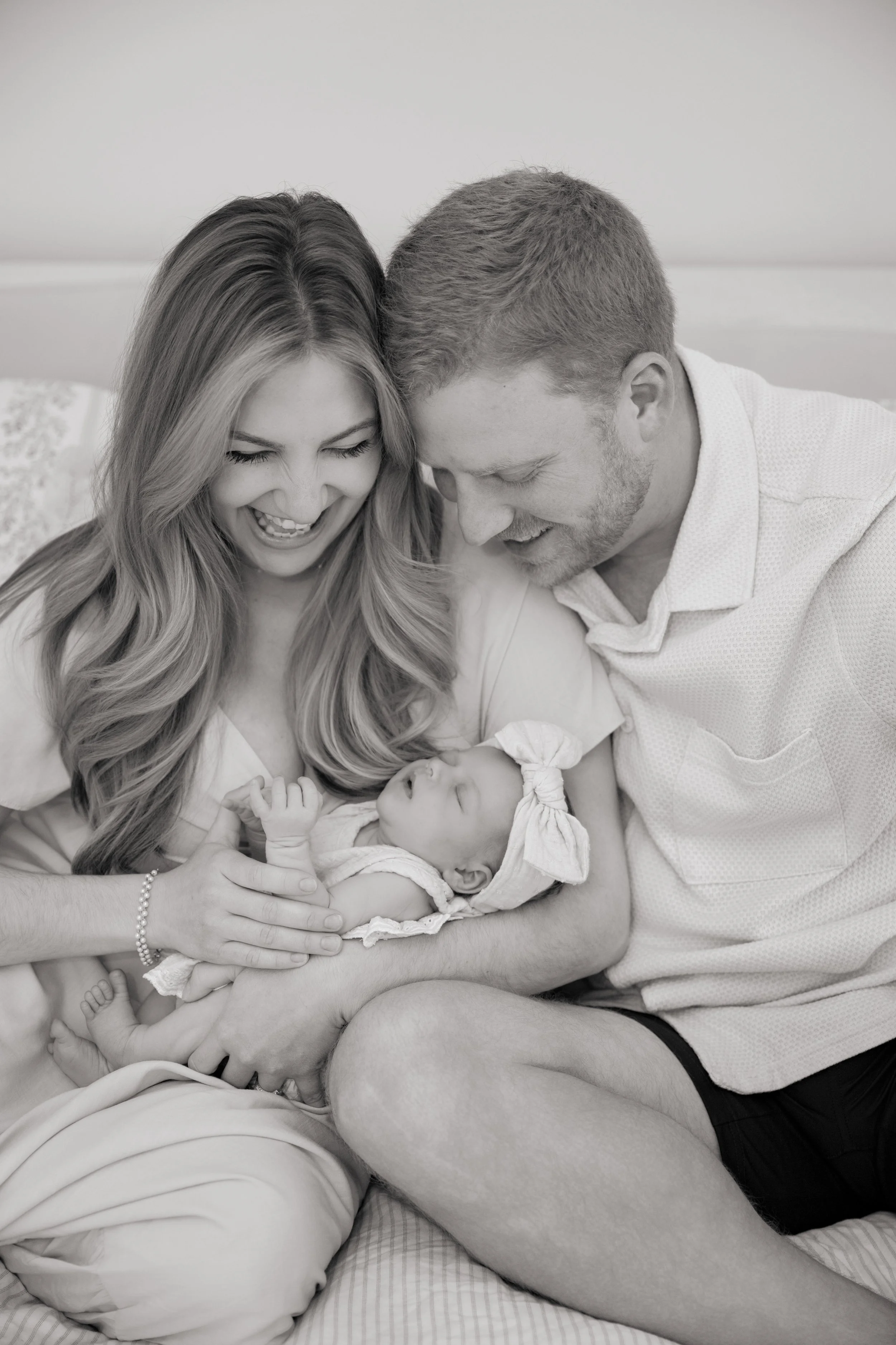 Mom, Dad, and baby snuggling on a bed