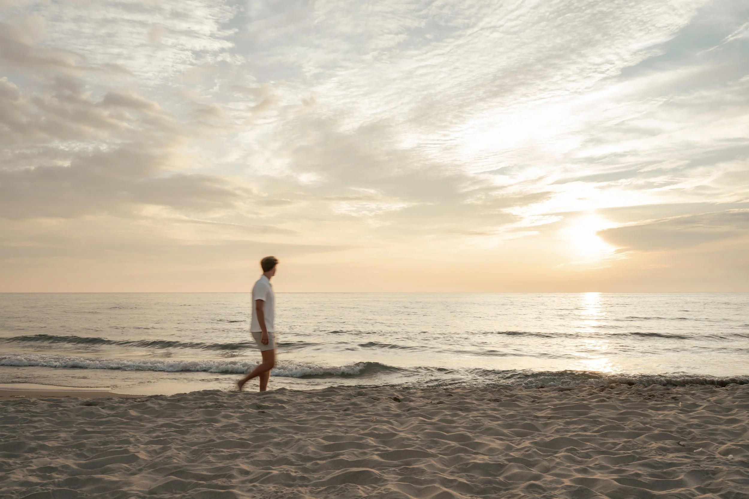 Senior guy sitting on a Lake Michigan beach at sunset