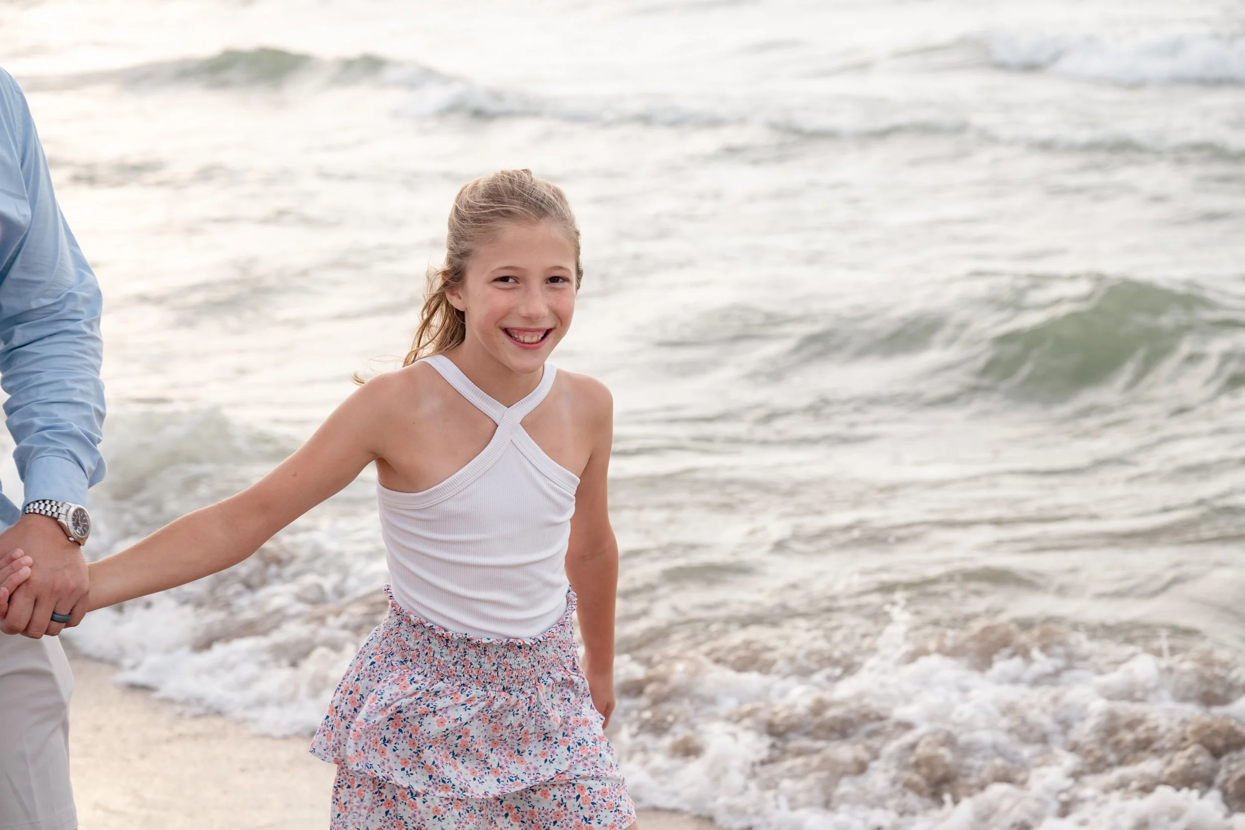 Young girl laughing as she plays in the Lake Michigan waves during a family session