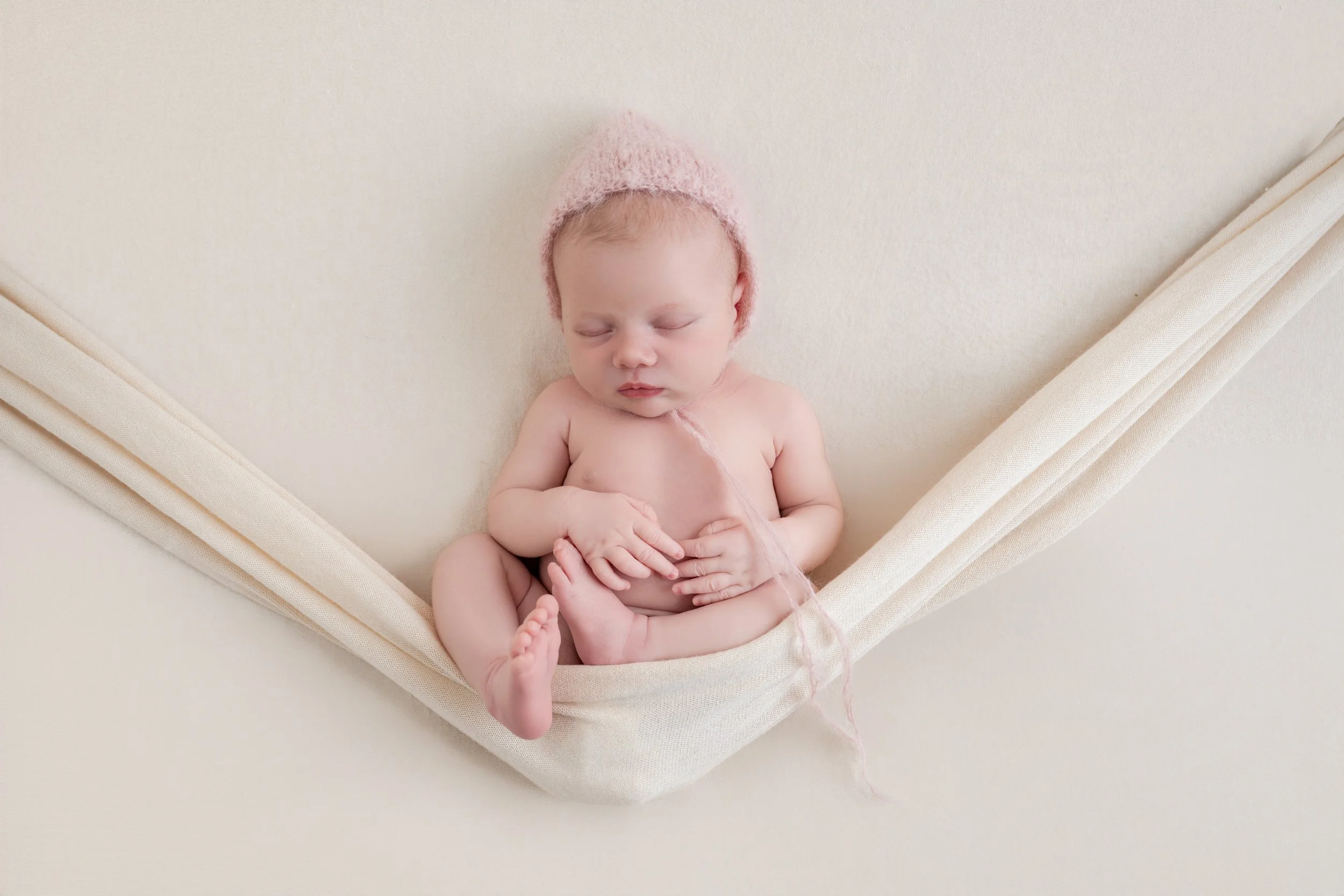 Newborn baby resting in a soft hammock during a studio newborn session