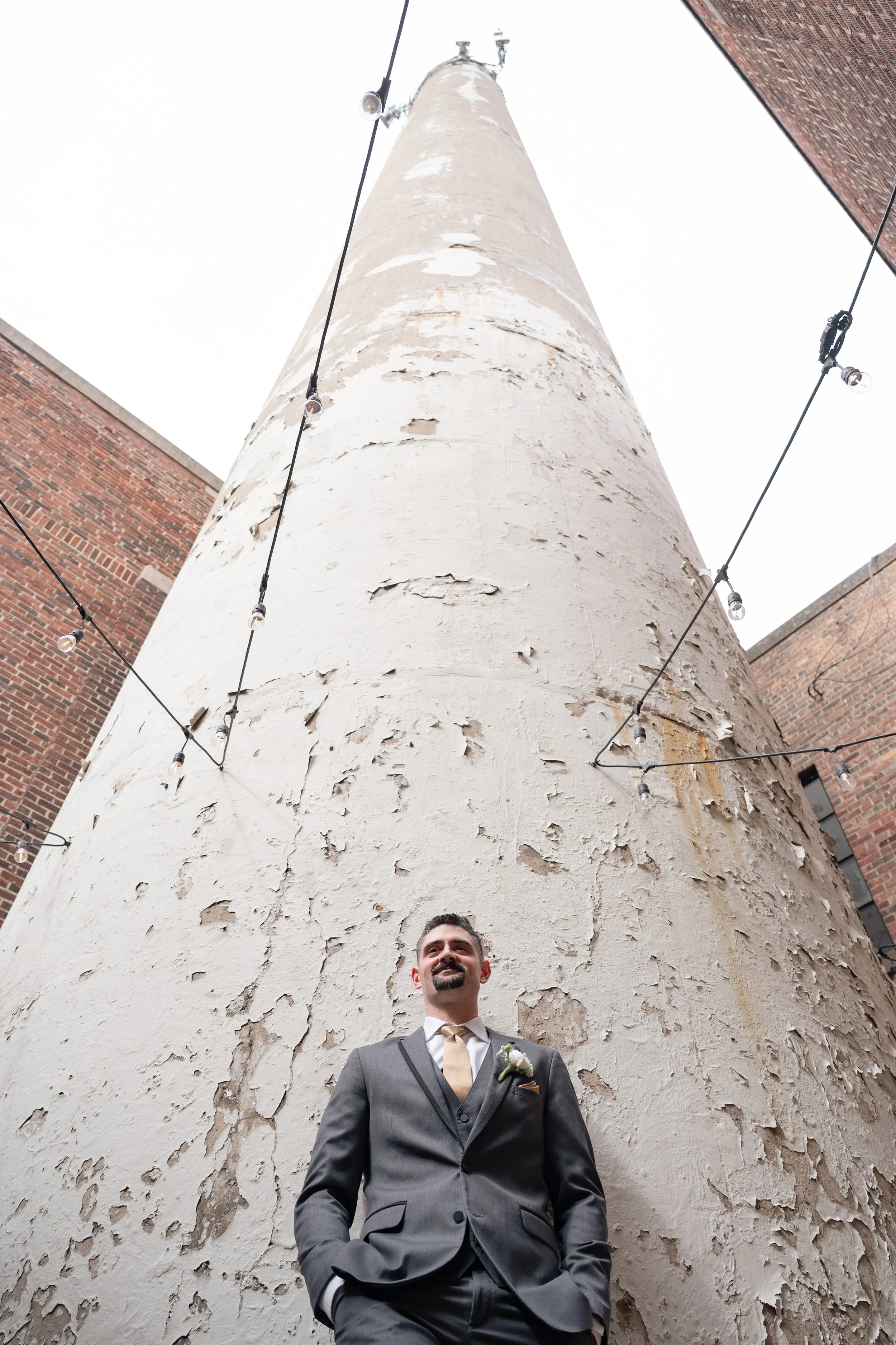 Groom standing by a tall tower.