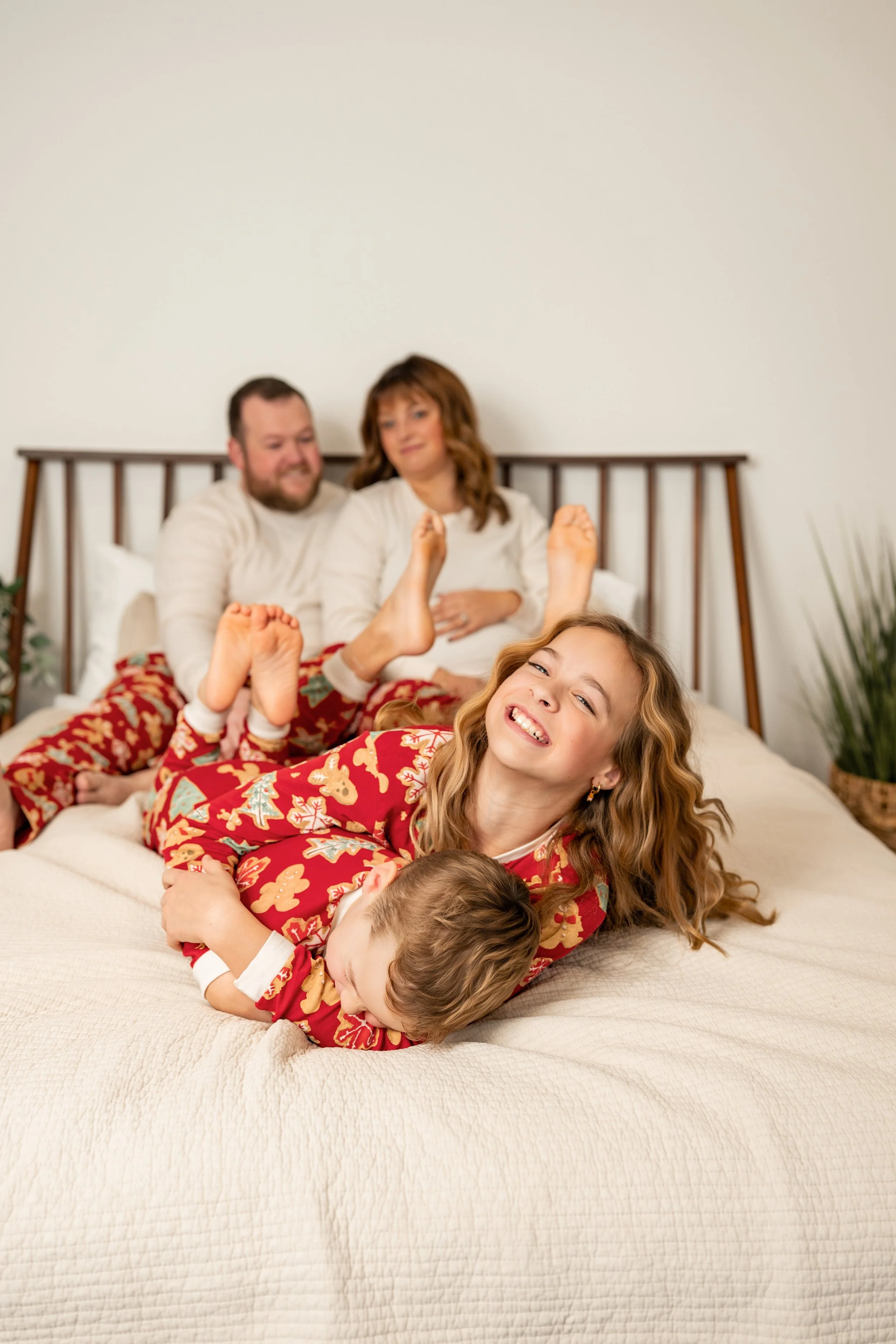 Family snuggling and hugging on a bed while wearing christmas pajamas, West Michigan Photographer