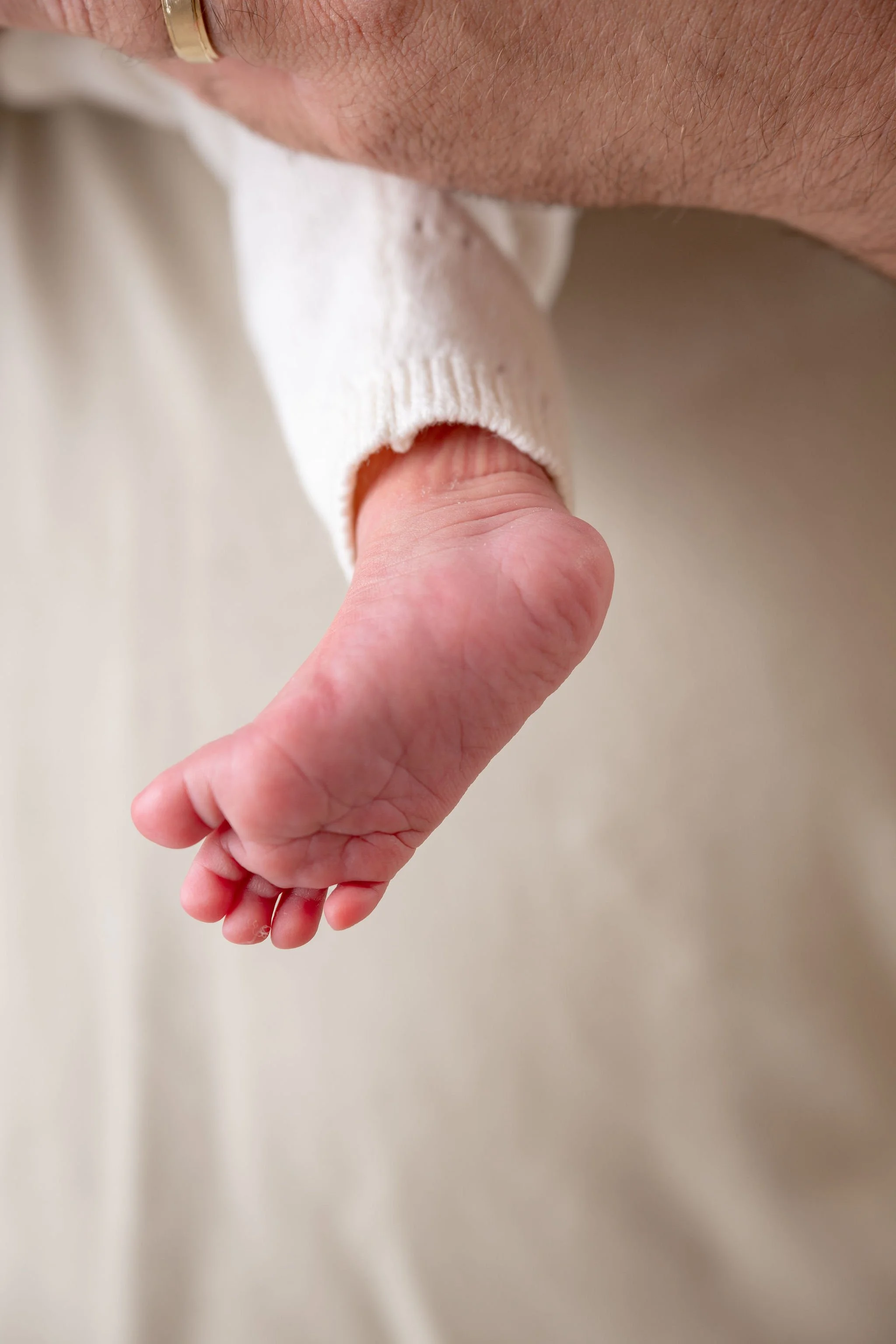 Close-up of a person's hand with the finger inserted into the mouth of a baby or small child.