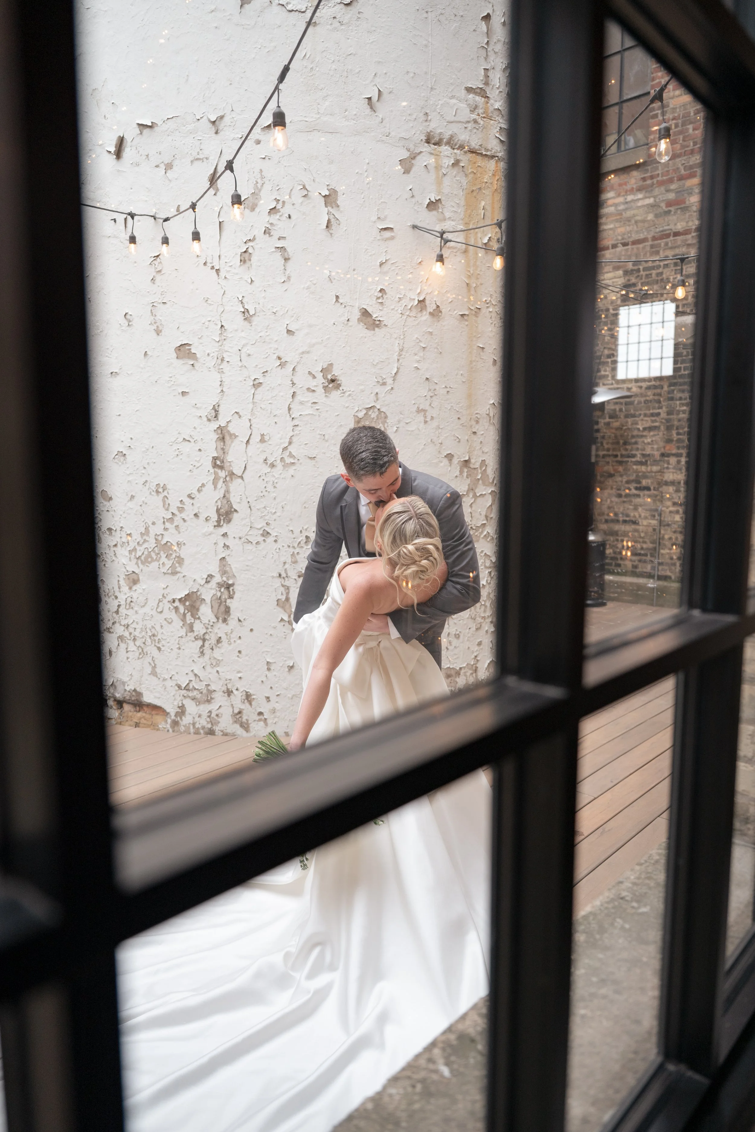Bride and groom kissing doing a dip through a vintage window. 