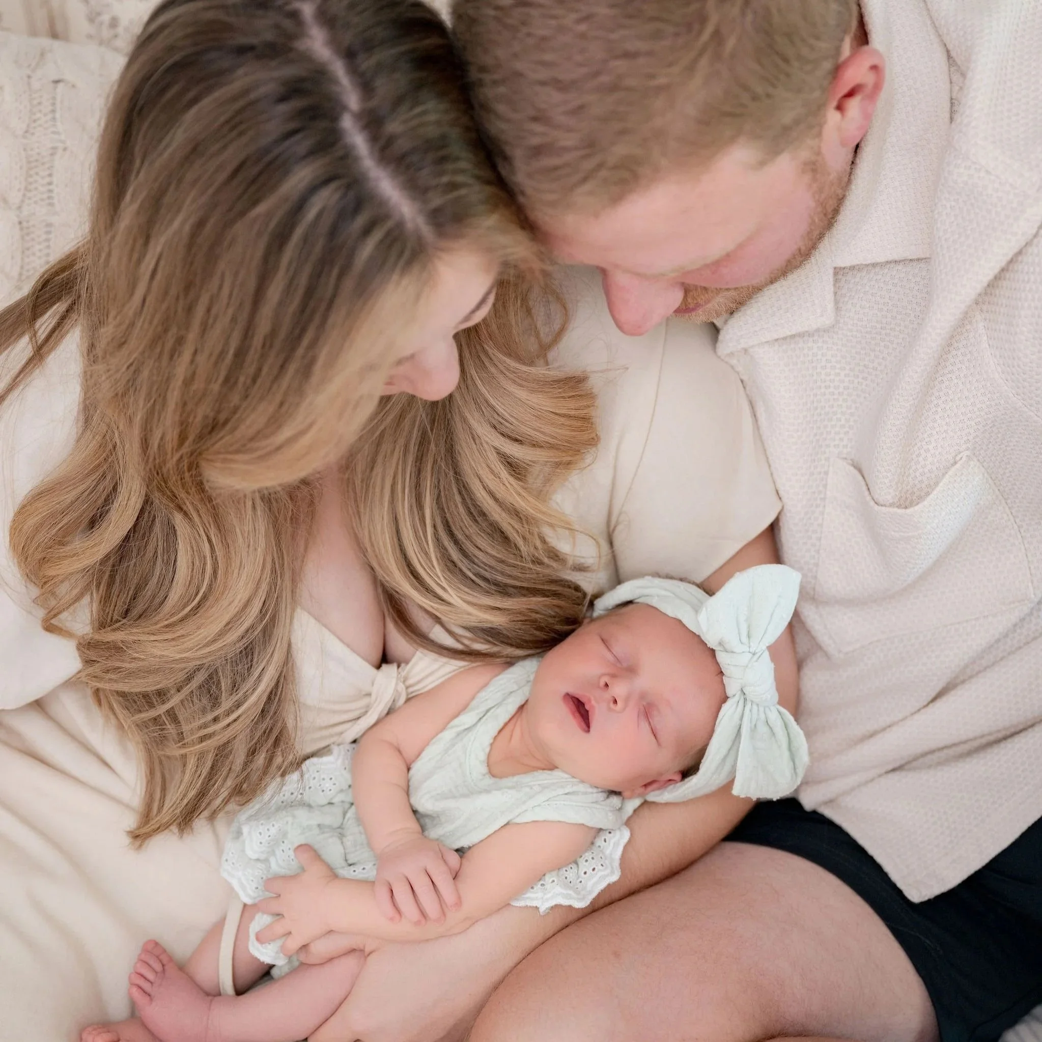 Mom, Dad, and baby snuggling while parents look at baby