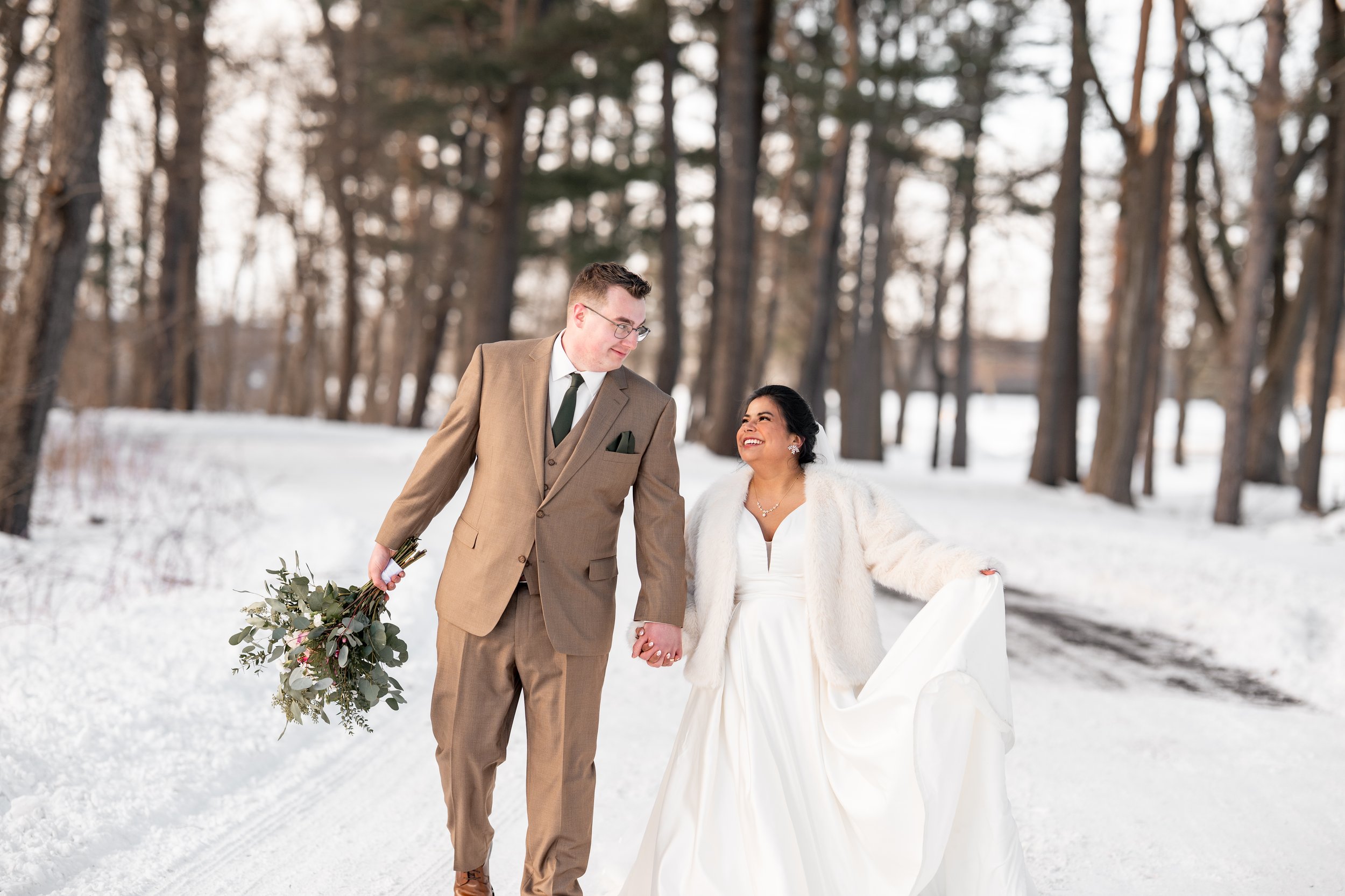 Bride and groom walking through a snowy Michigan forest on their winter wedding day