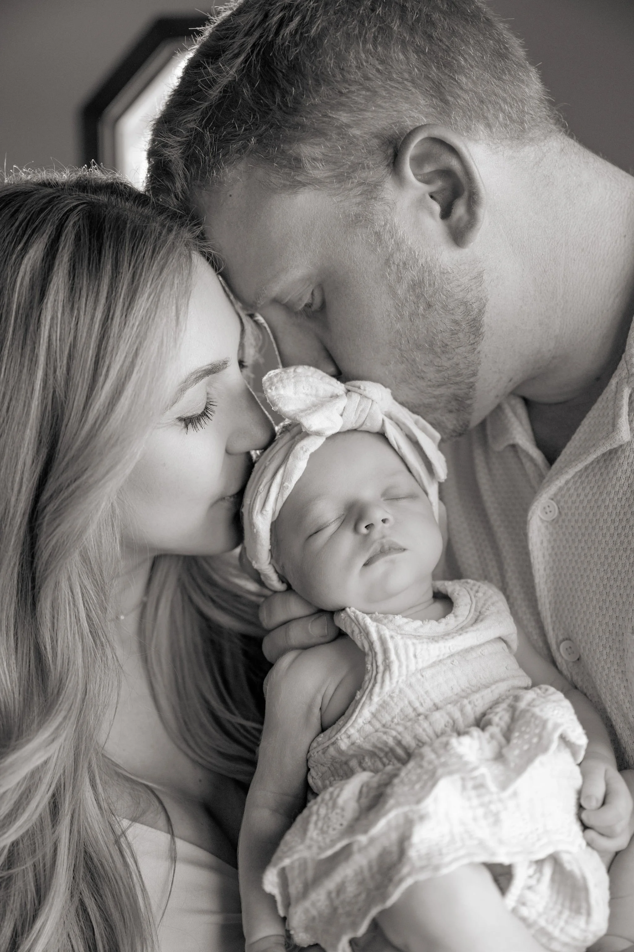 new parents kissing baby on the head.