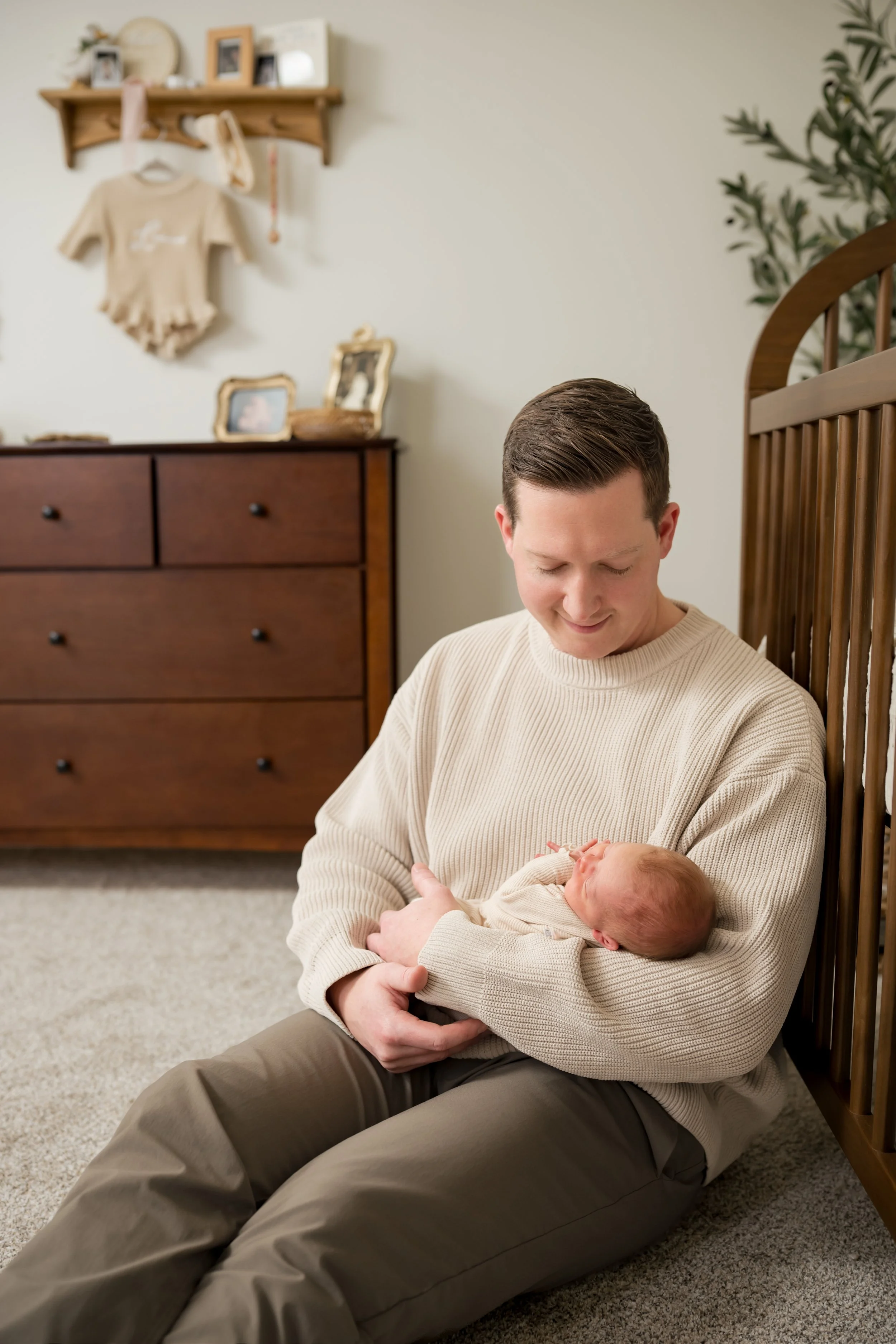 a dad holding their newborn baby in the nursery Michigan Lifestyle newborn photography