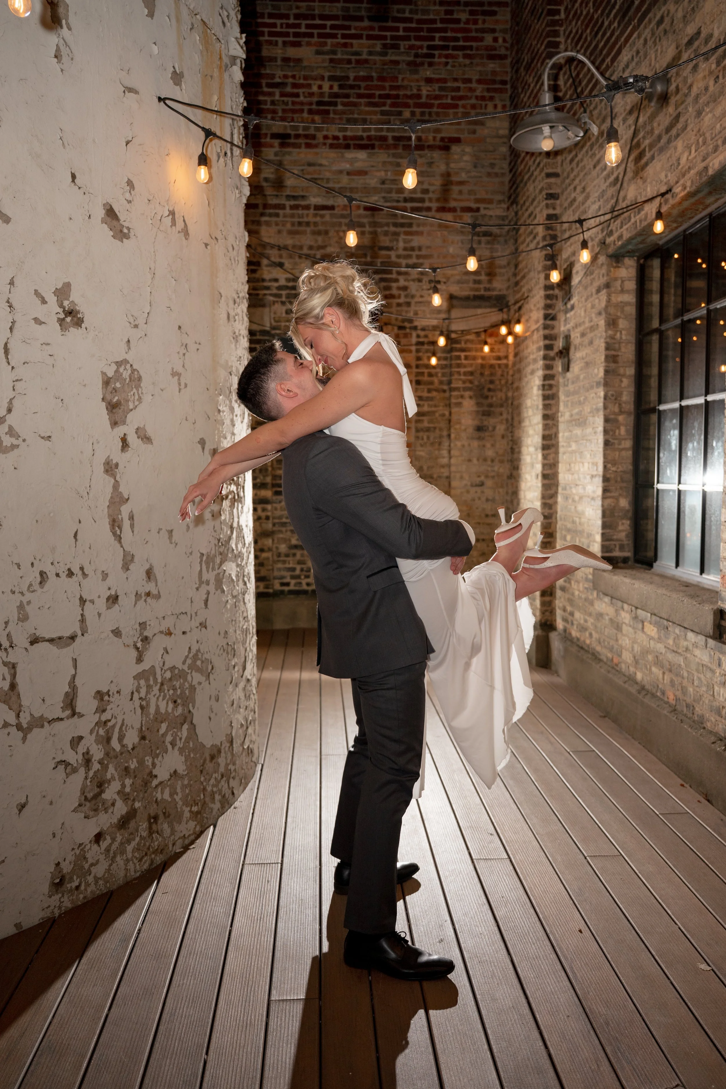 Groom holding the bride up and kissing outside at New Vintage Place in Grand Rapids Michigan.