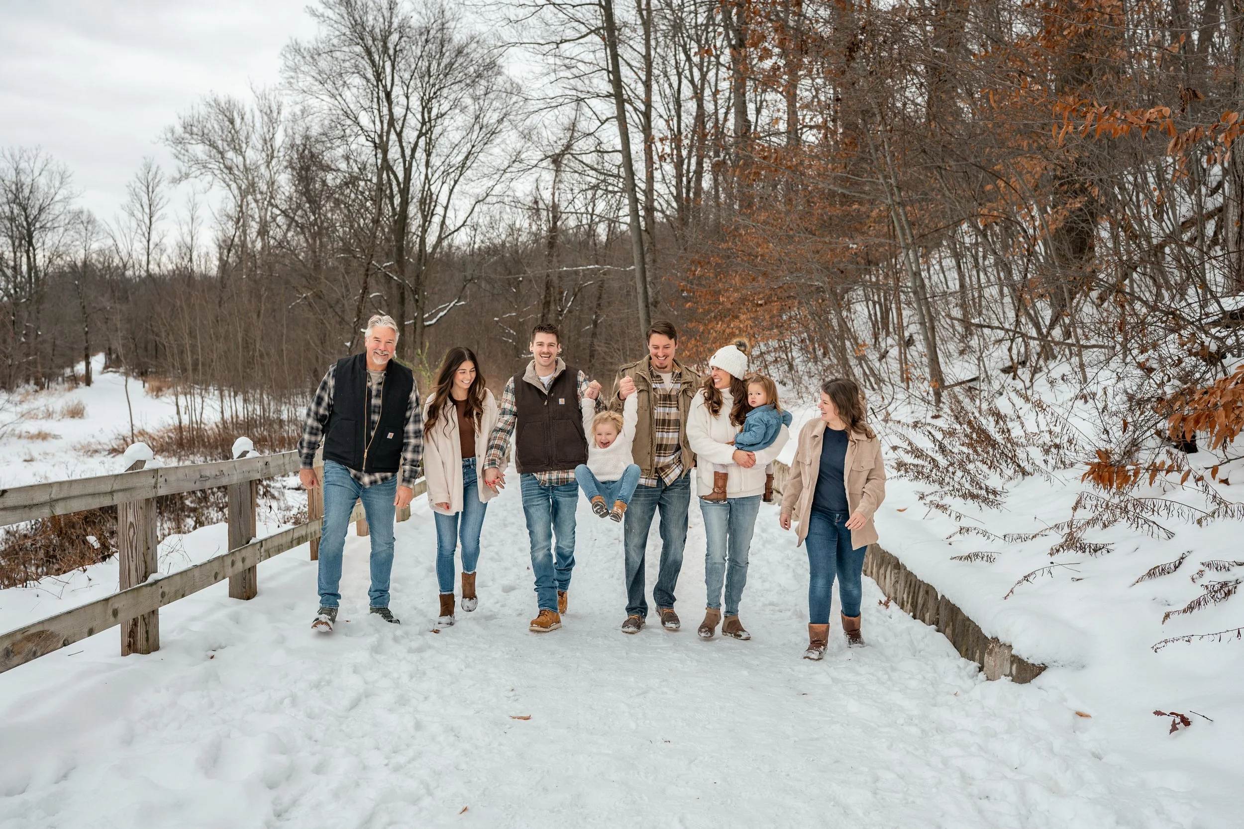 A family walking down a snowy path looking at each other and playing with kids West Michigan family photography