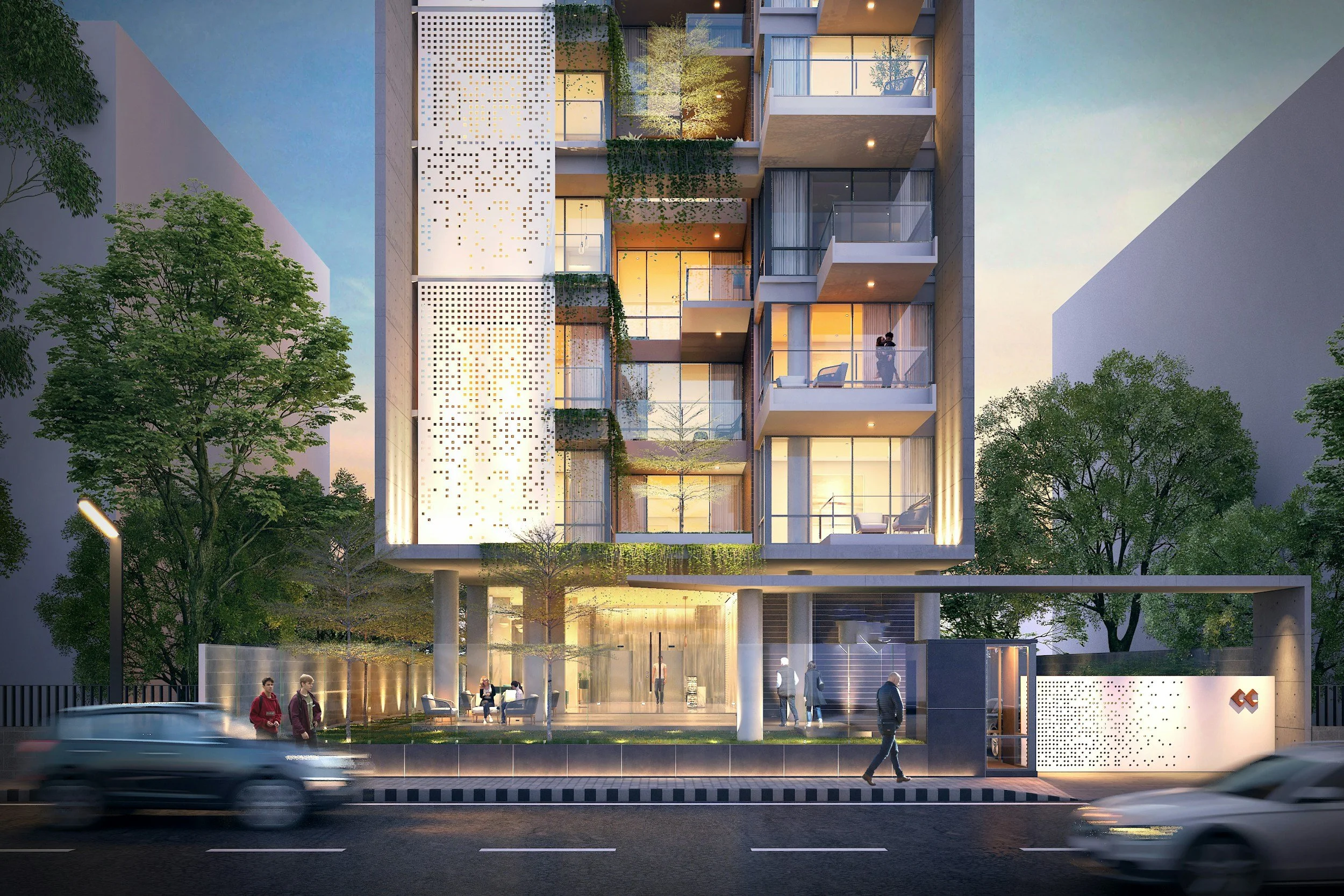 Modern multi-story building with large glass windows and balconies, surrounded by trees, illuminated at dusk, with pedestrians and cars on the street.