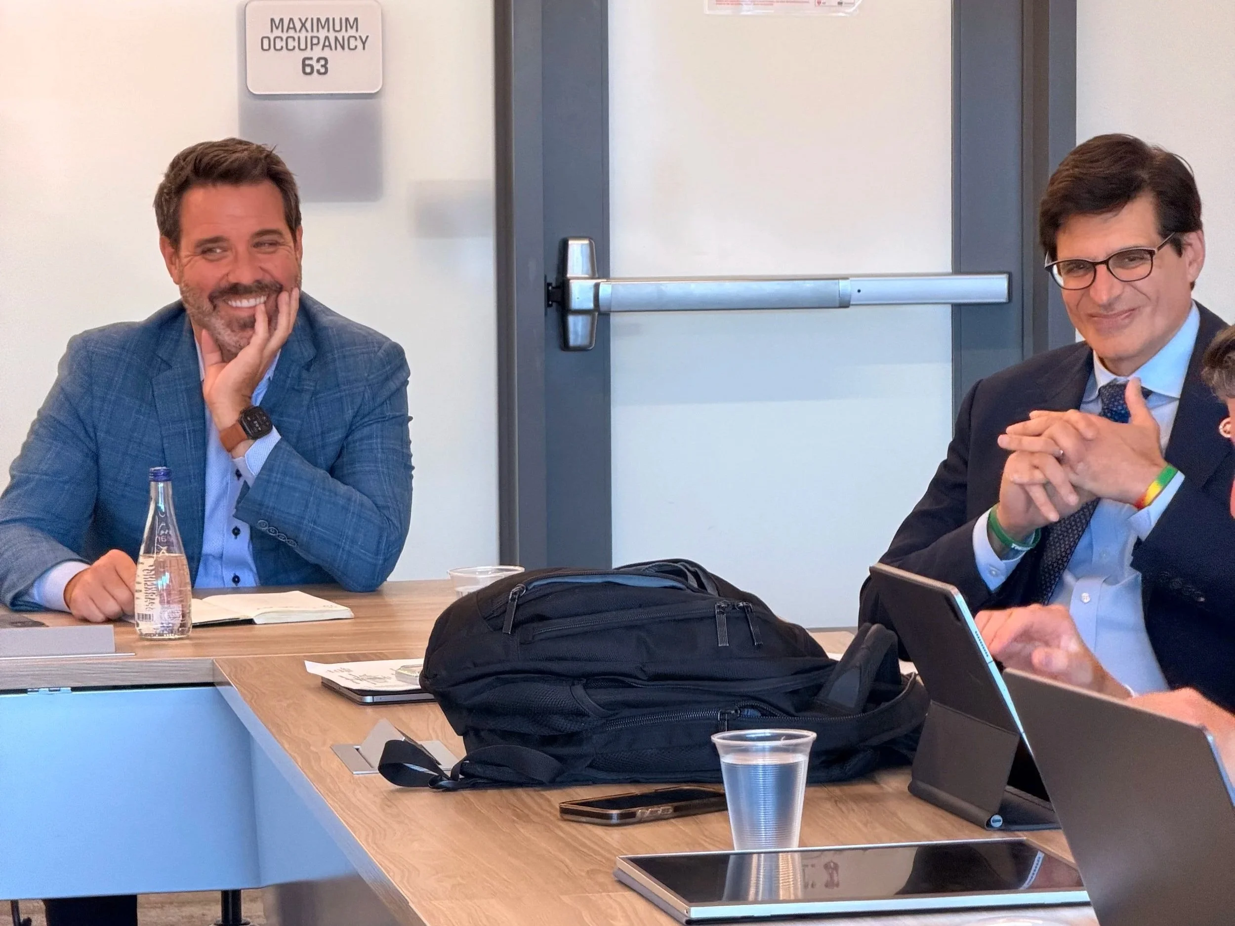 Two men sitting at a table smiling.