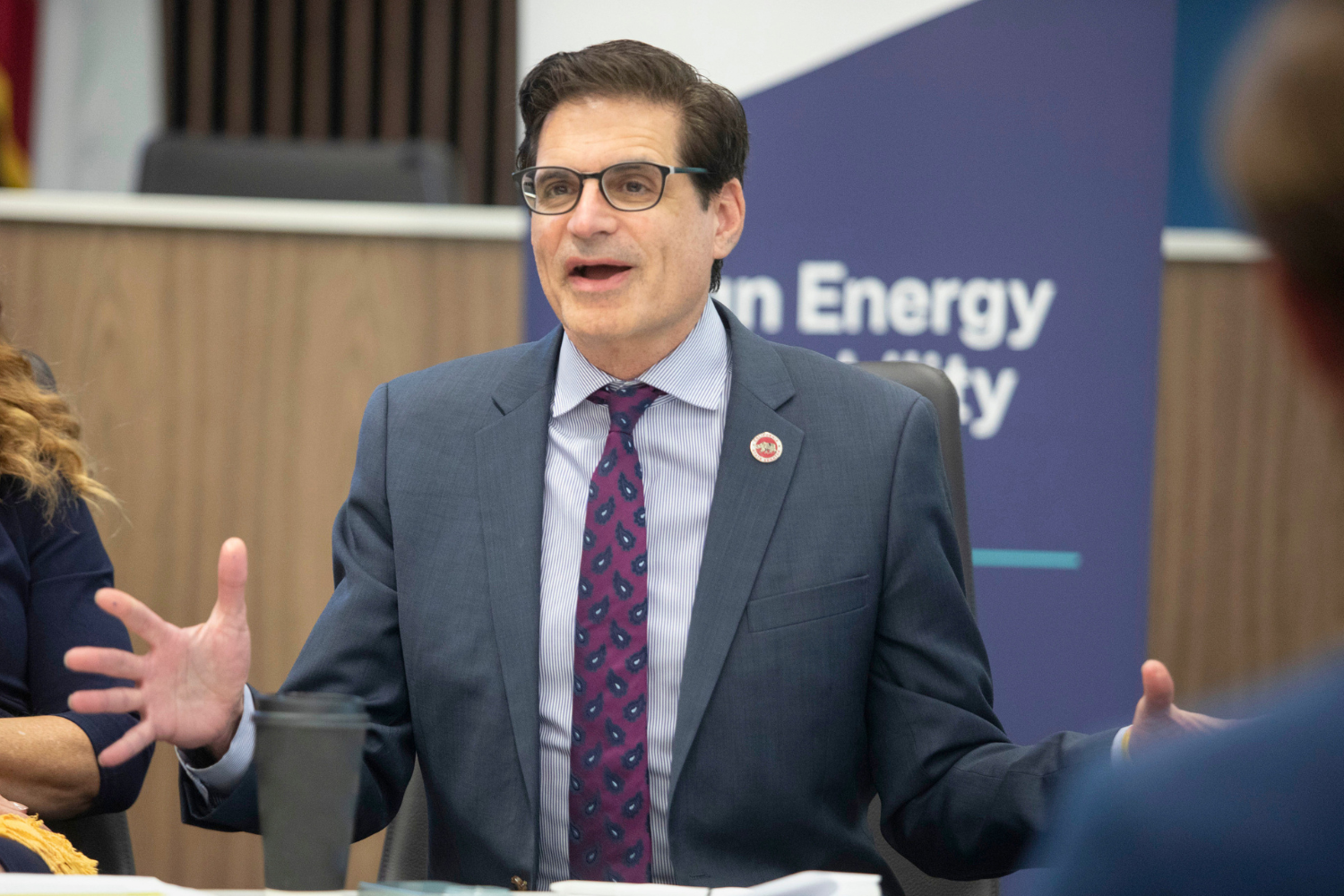 Senator Josh Becker speaking at a desk, with is hands gesturing wide.
