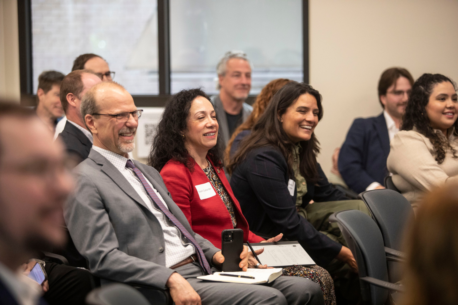 Three people smile and laugh while seated at a summit.