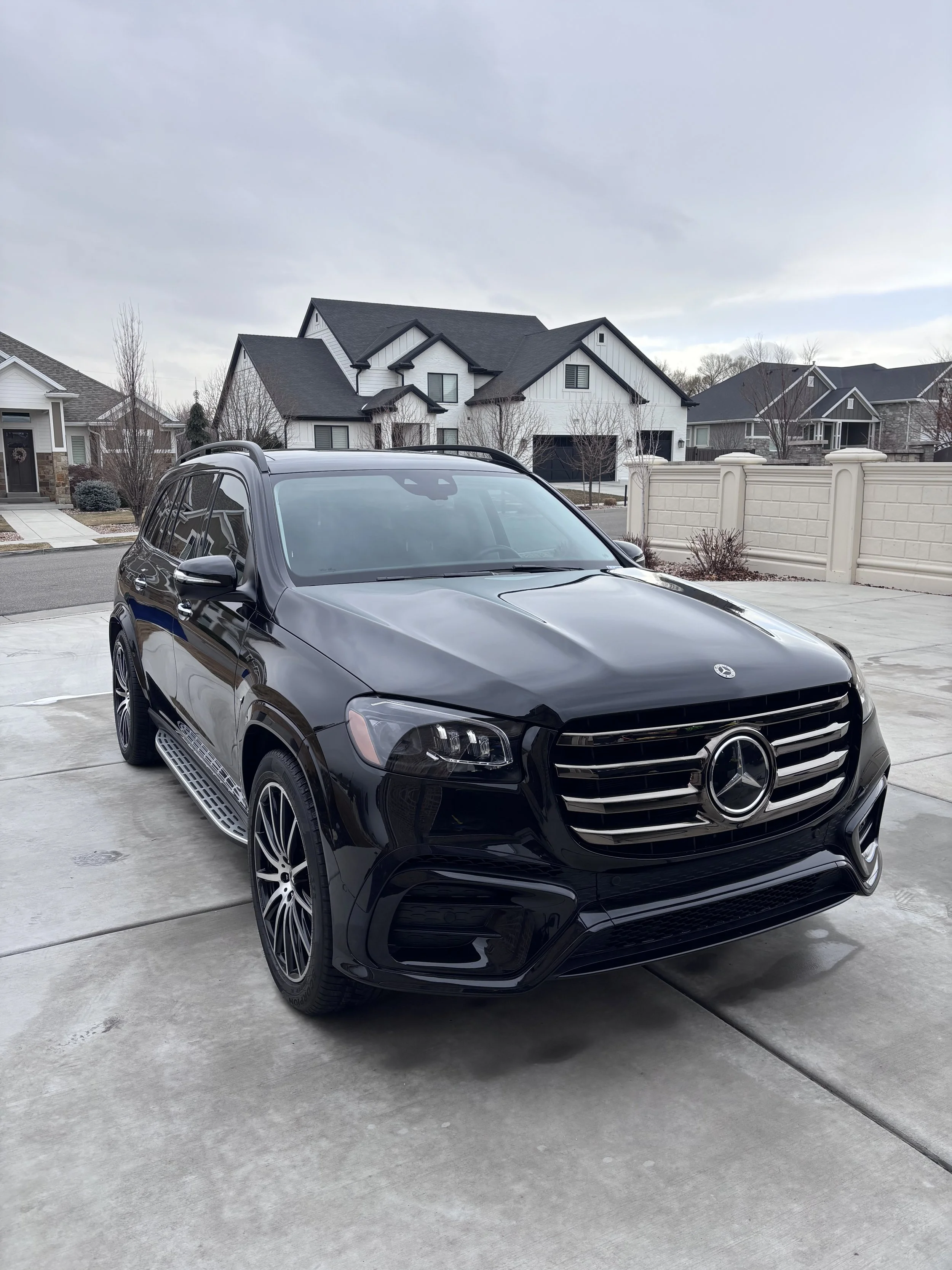 Black Mercedes-Benz SUV parked in a driveway with modern suburban houses in the background.