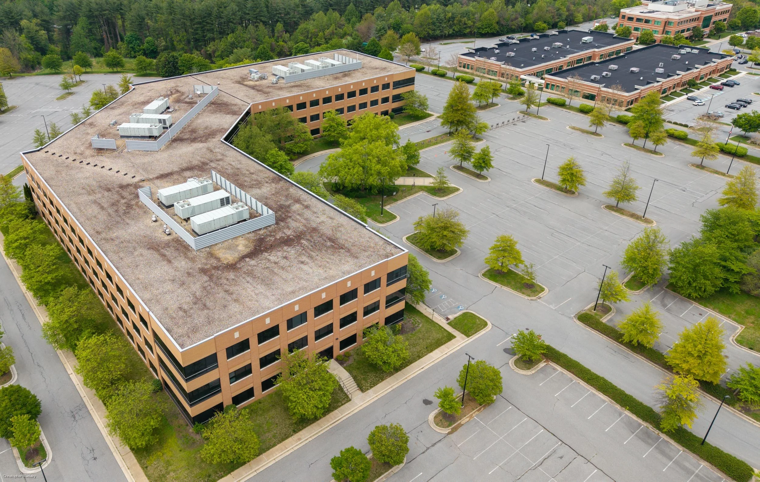 Commercial Roof & Property Detail — Close aerial of office building showing rooftop equipment, parking layout, and site access — Sparks, MD.