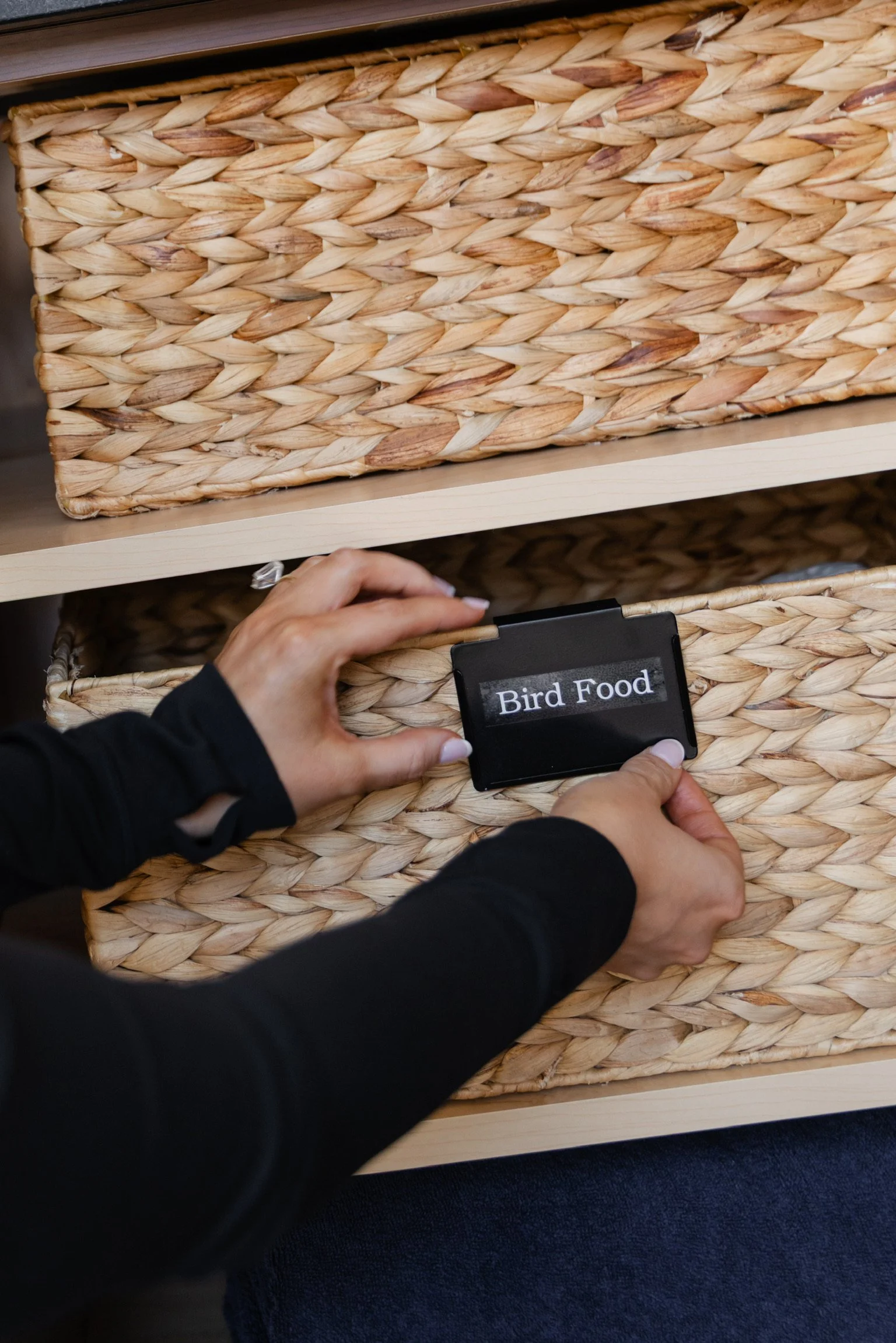 Labeling and placing a "Bird Food" container into a wicker drawer — professional decluttering services, Atlanta