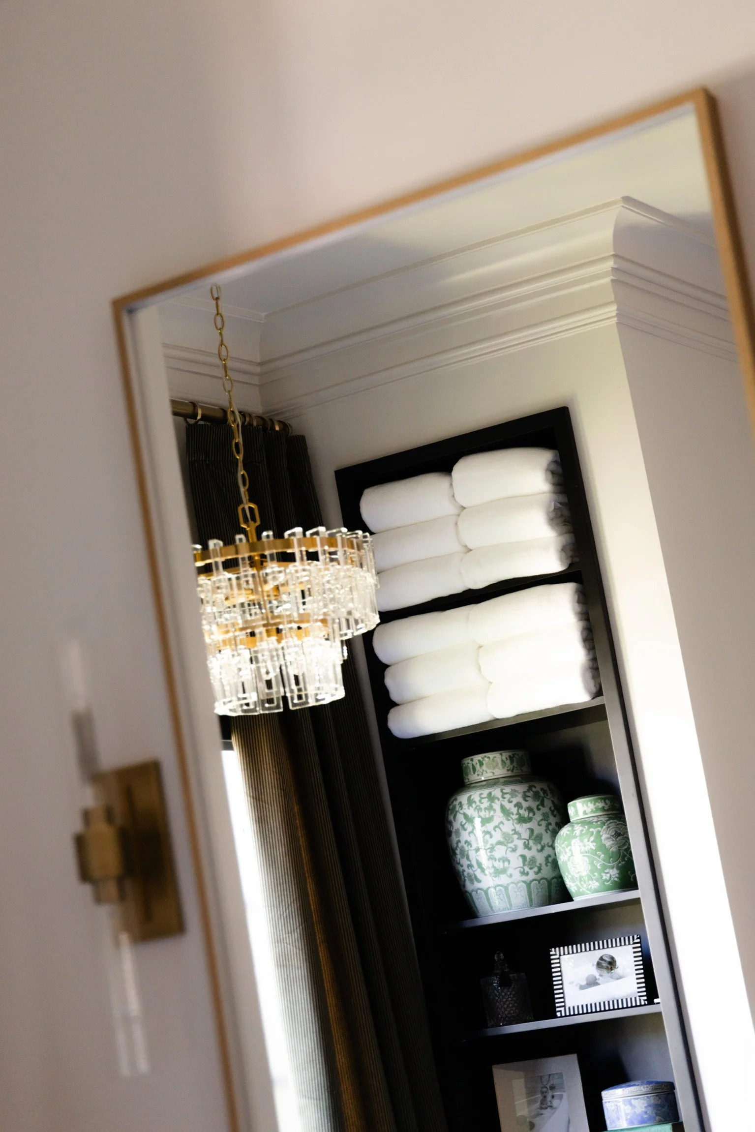 Reflected shelving styled with towels and jars, crown molding detail — luxury organization, Atlanta.