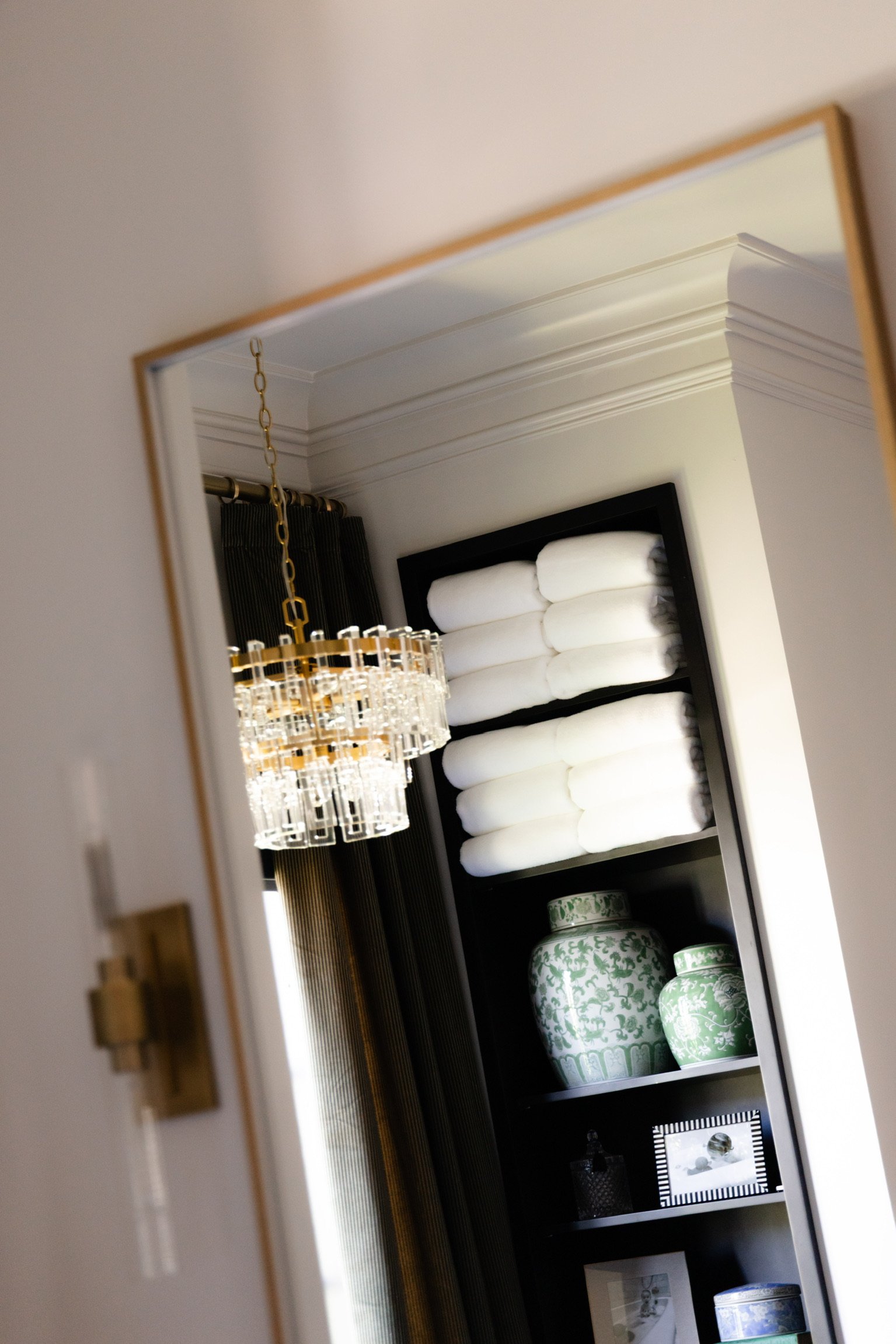 Reflected view of an organized shelf with towels and decorative jars — white glove home organization, North Atlanta.