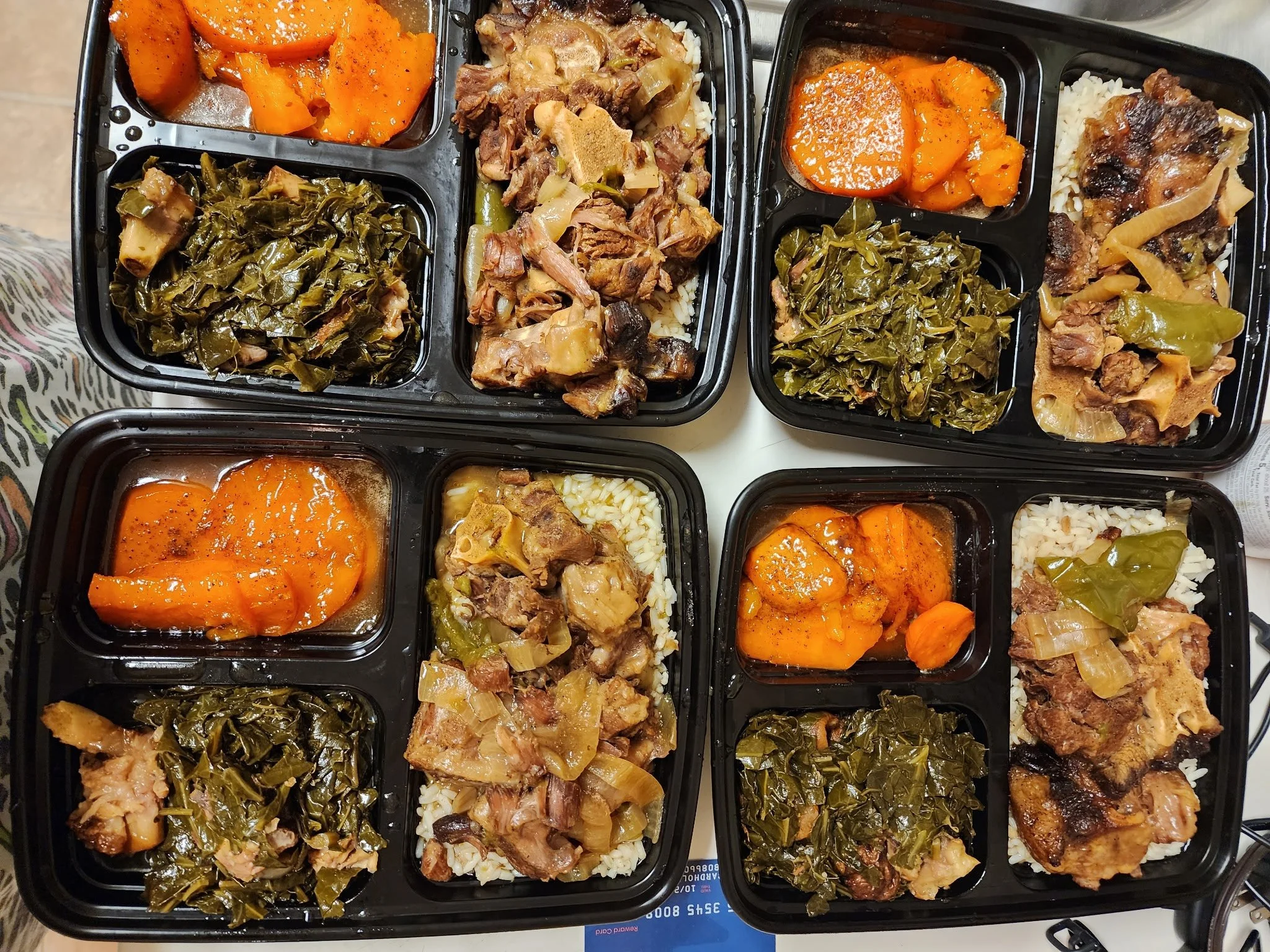 Four meal prep containers filled with cooked vegetables, rice, and meat dishes, including carrots, greens, and stewed meat.