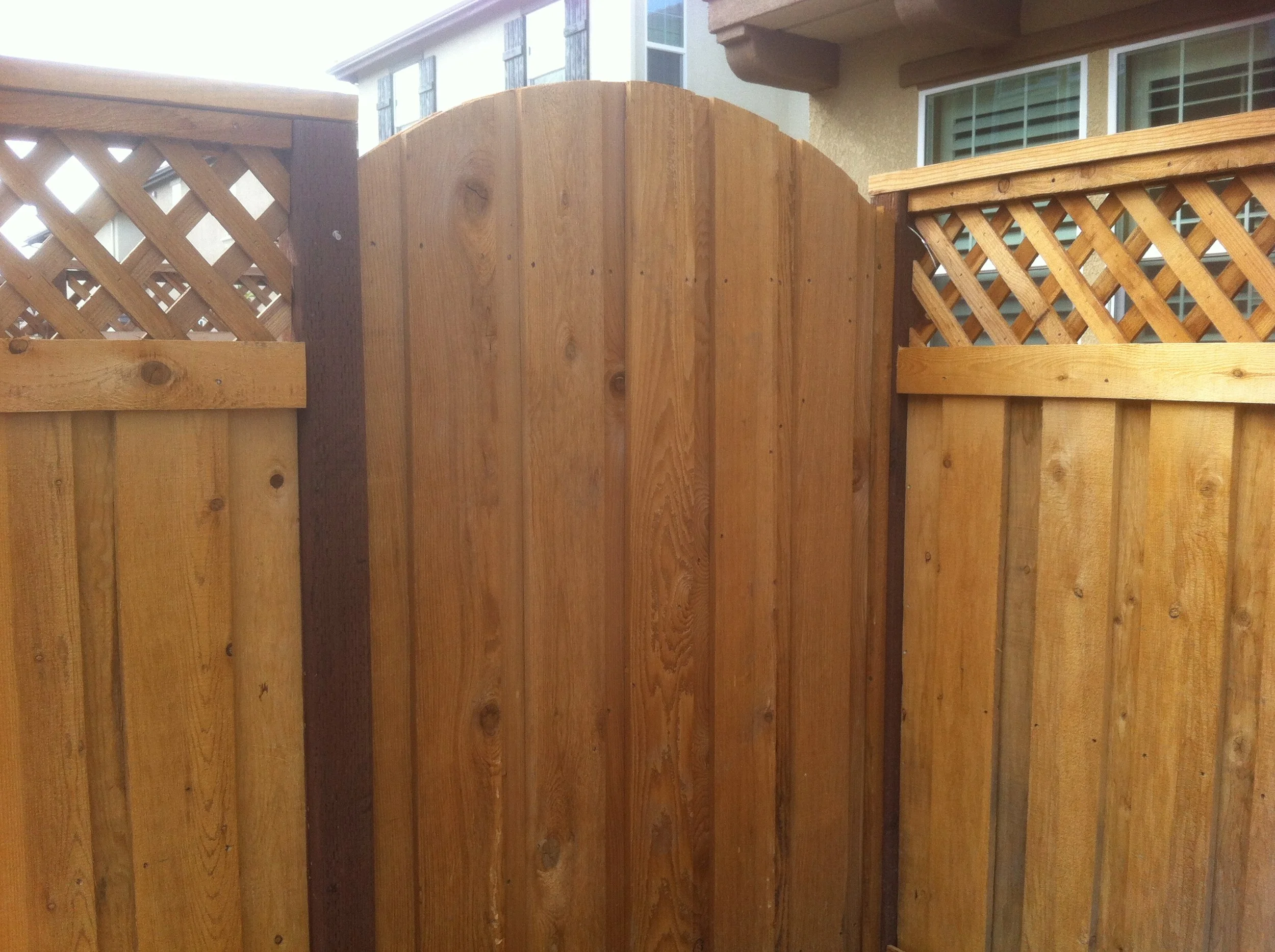 A wooden privacy fence with lattice panels in a residential backyard.