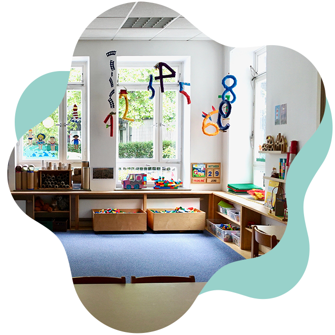 Kinderzimmer mit Spielmaterialien, Hundespielzeug, Spielen und Dekorationen wie bunte Zahlen und Figuren an den Fenstern.