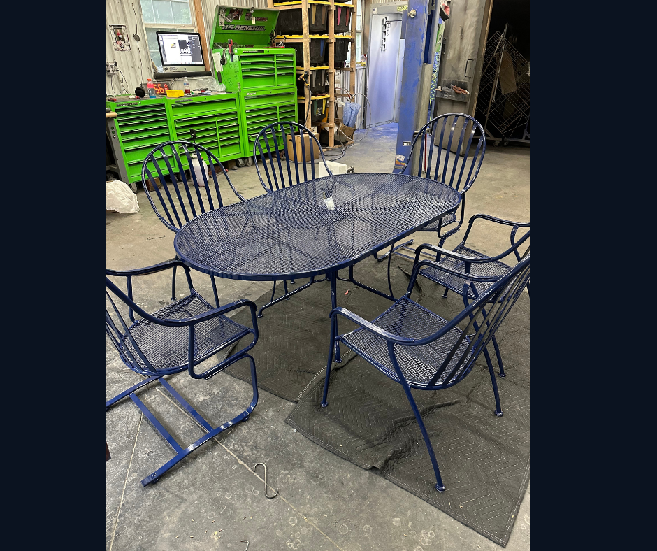 Blue metal outdoor patio dining set with one rectangular table and six chairs in a workshop or garage setting.