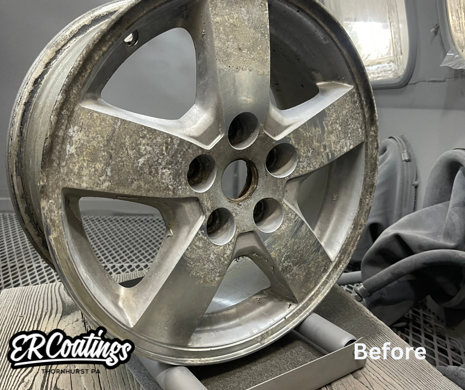 A dirty, tarnished car wheel rim before cleaning, with visible dirt and corrosion. The rim is silver with five spokes and is placed on a stand for cleaning.
