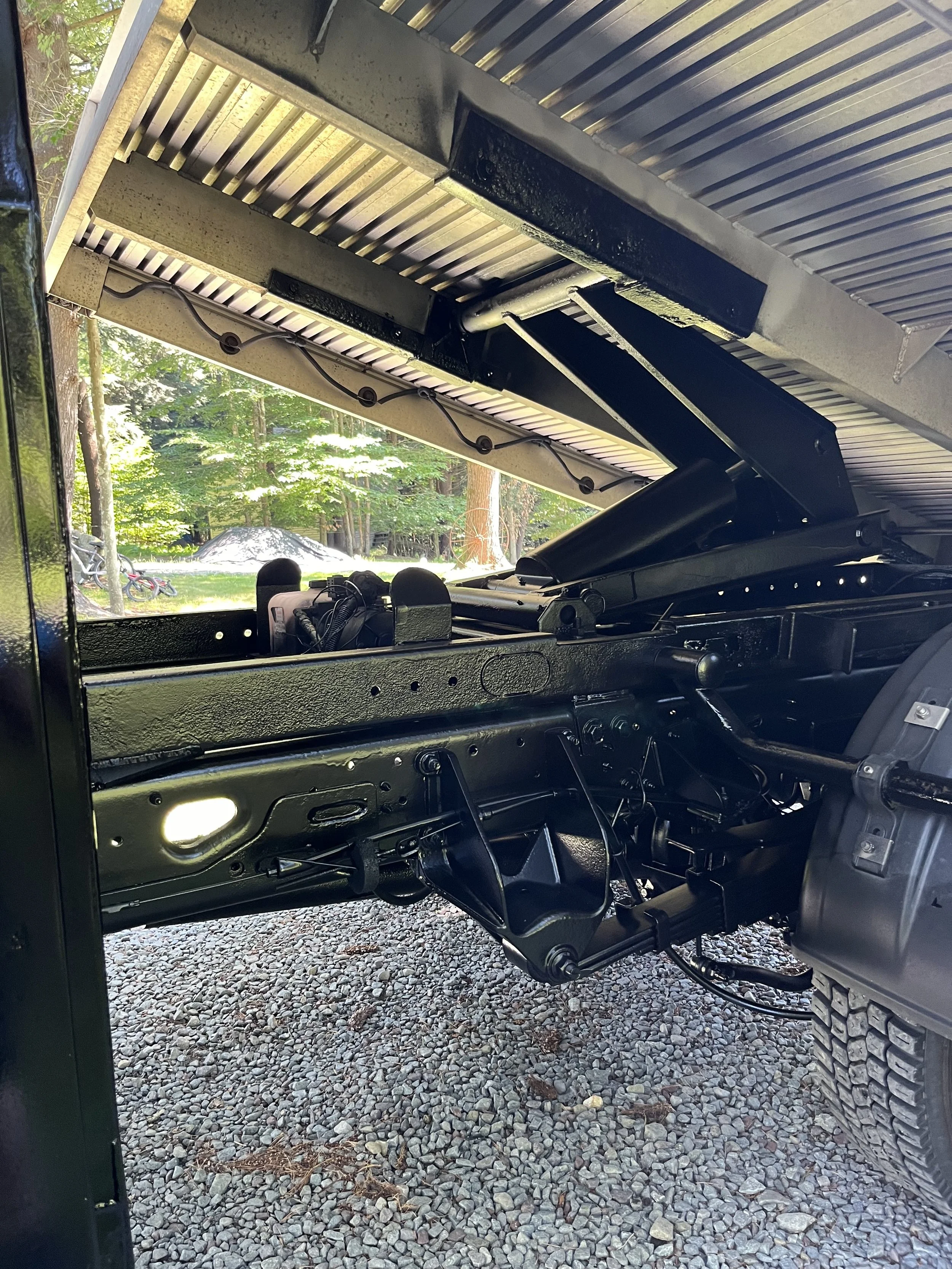 Close-up of the underside of a truck bed lifted to reveal the mechanical components and suspension system.
