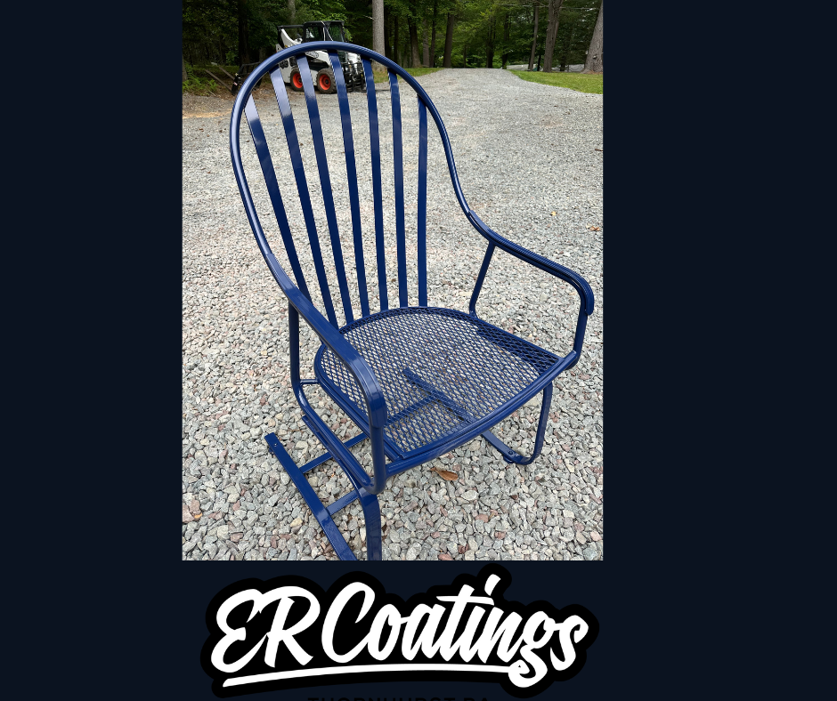 Blue metal rocking chair on a gravel pathway in a wooded outdoor area.