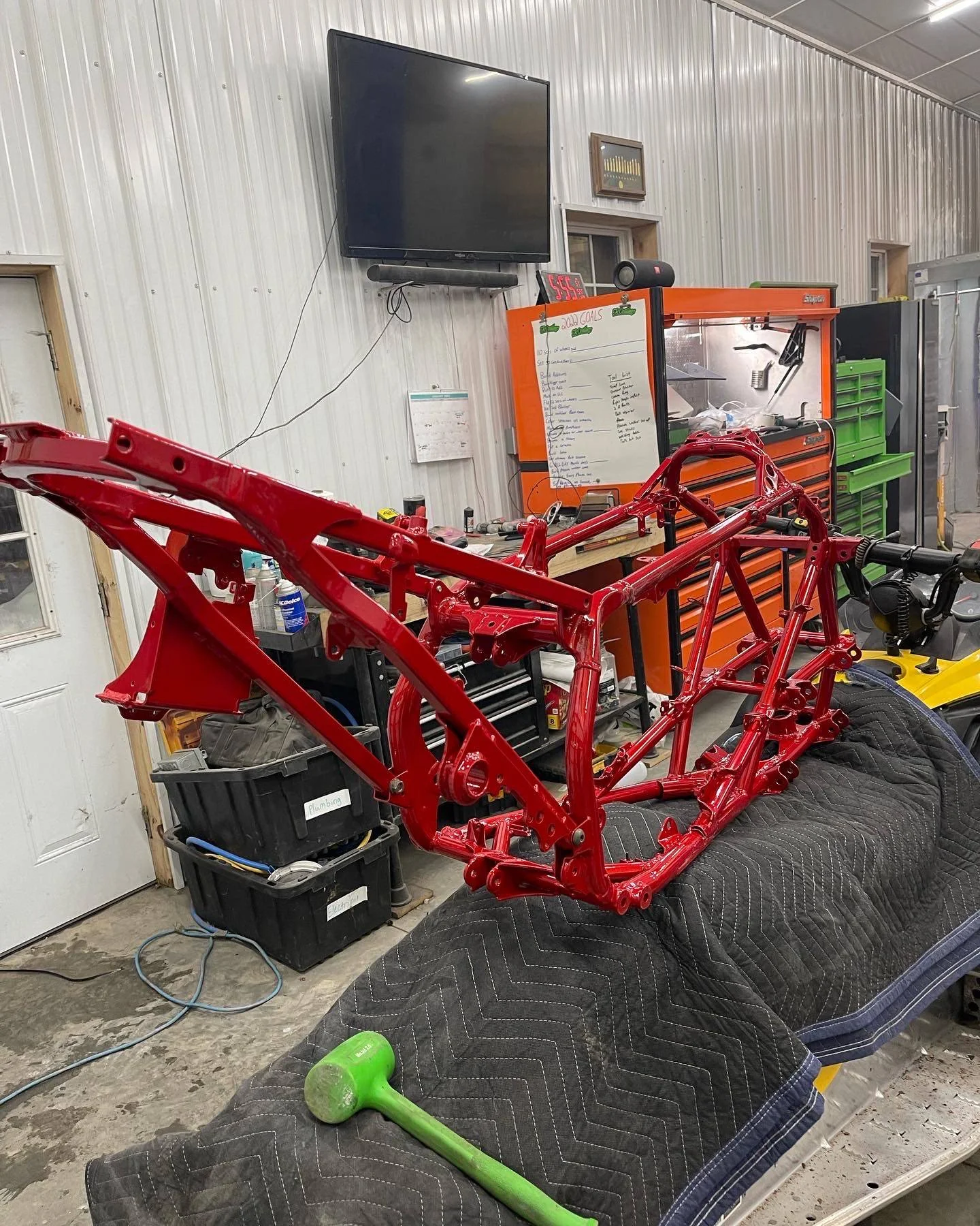 Red motorcycle frame on a workbench inside a garage or workshop.