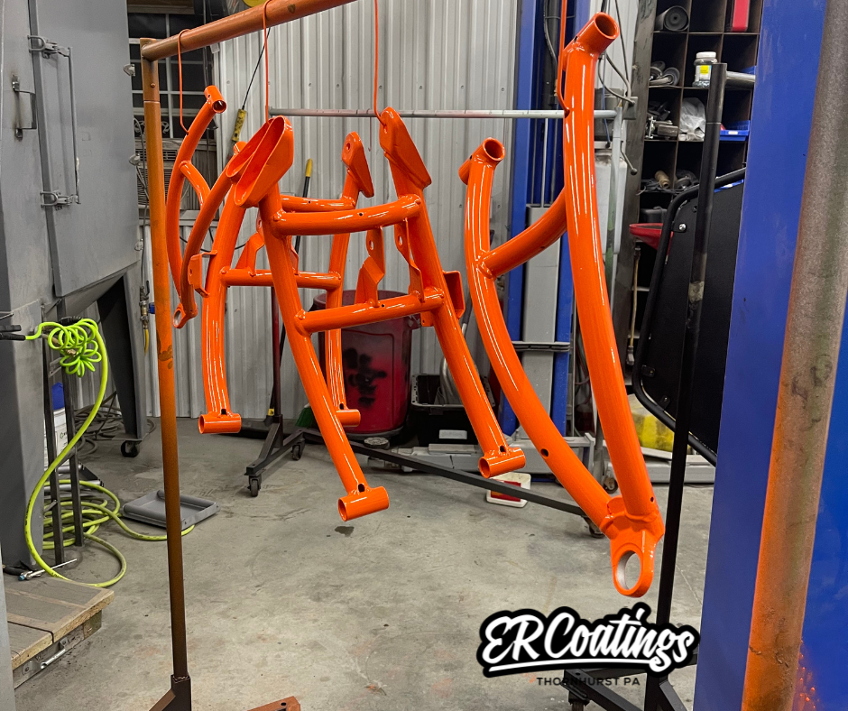 Orange painted bicycle frame parts hanging in a workshop.